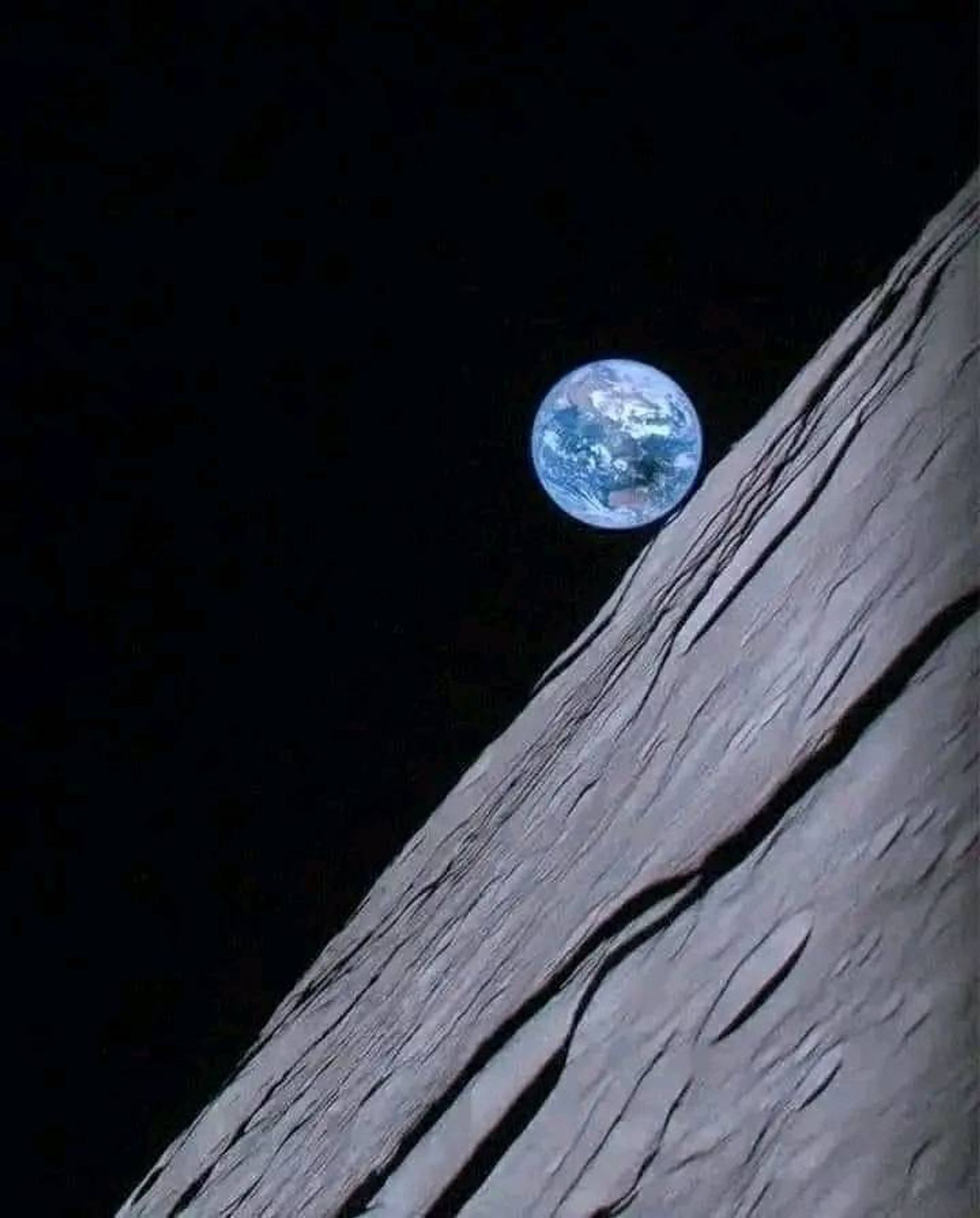 Photo d'une éclipse solaire sur l'Australie prise à partir de la lune
La photo se partage en deux parties, avec une diagonale qui va du coin droit en haut au coin gauche en bas et qui est occupée par la surface grise de la lune, de l'autre côté, du noir, et la terre, petite bille bleue avec une tache sur l'Australie