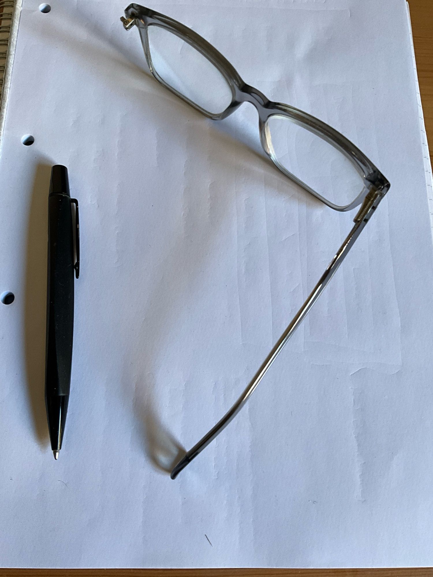 Broken pair of reading glasses and a pen