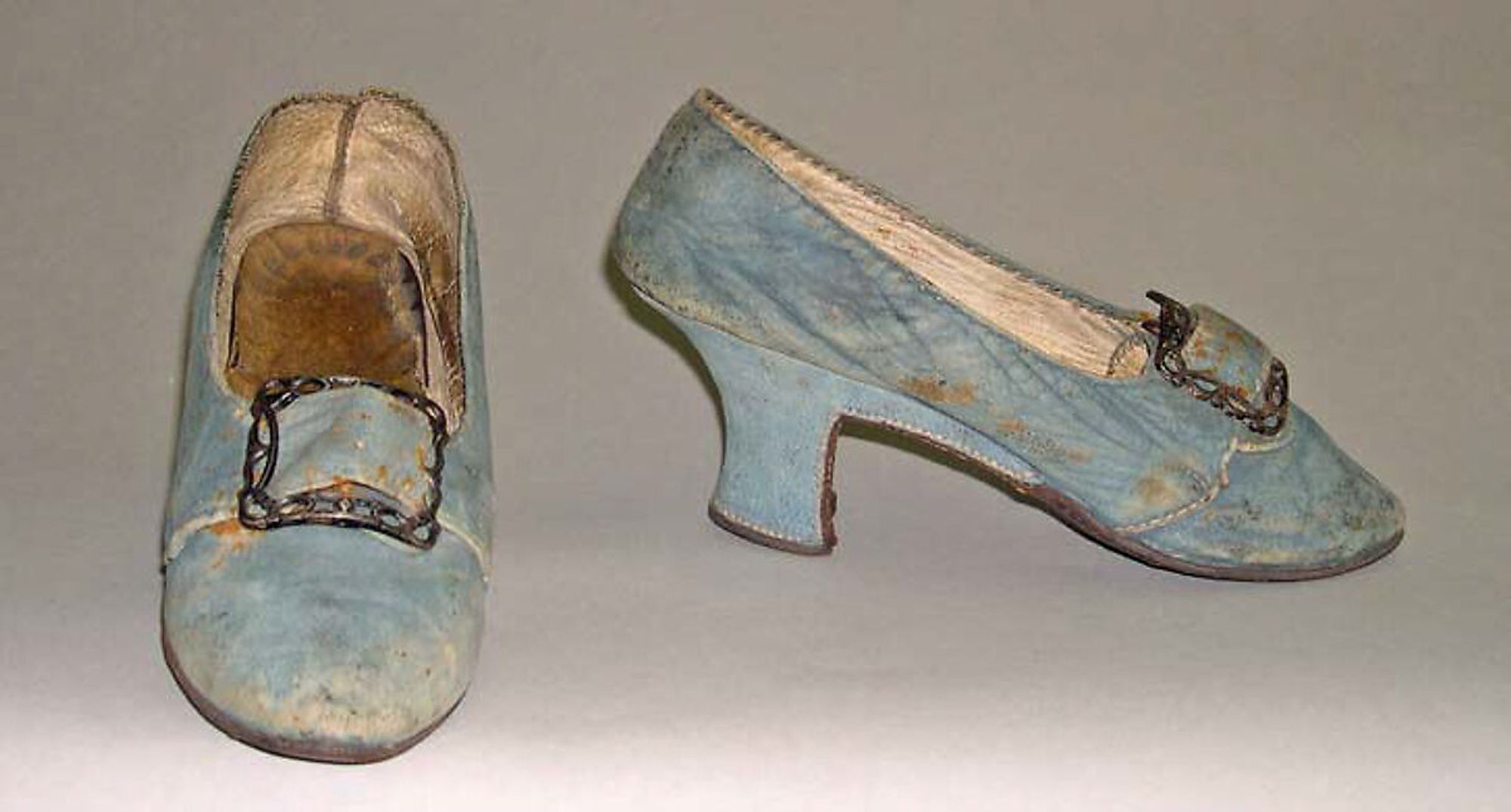 A pair of dirty and worn 1780s blue pumps.