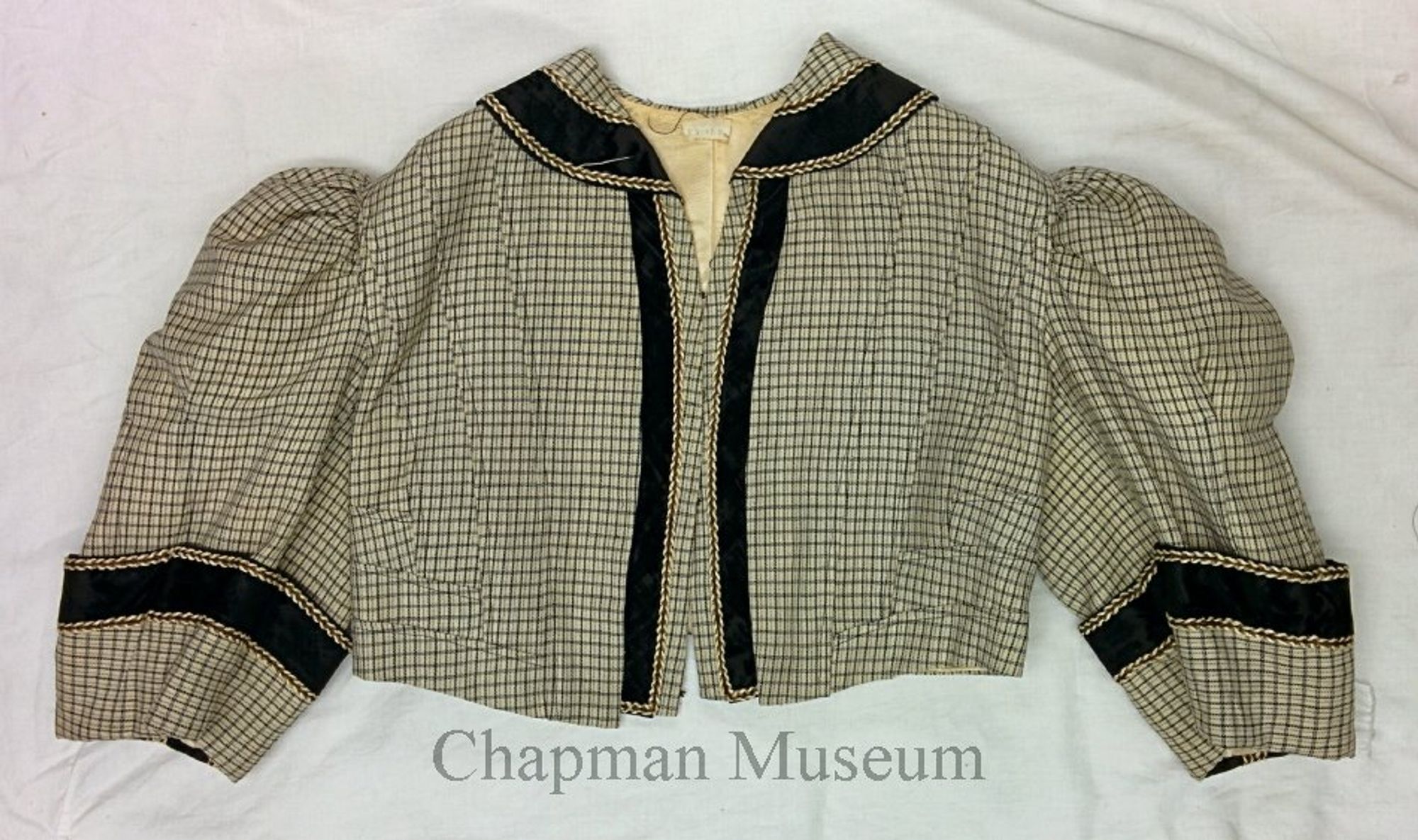 Photo of a checked short jacket with black velvet trim.