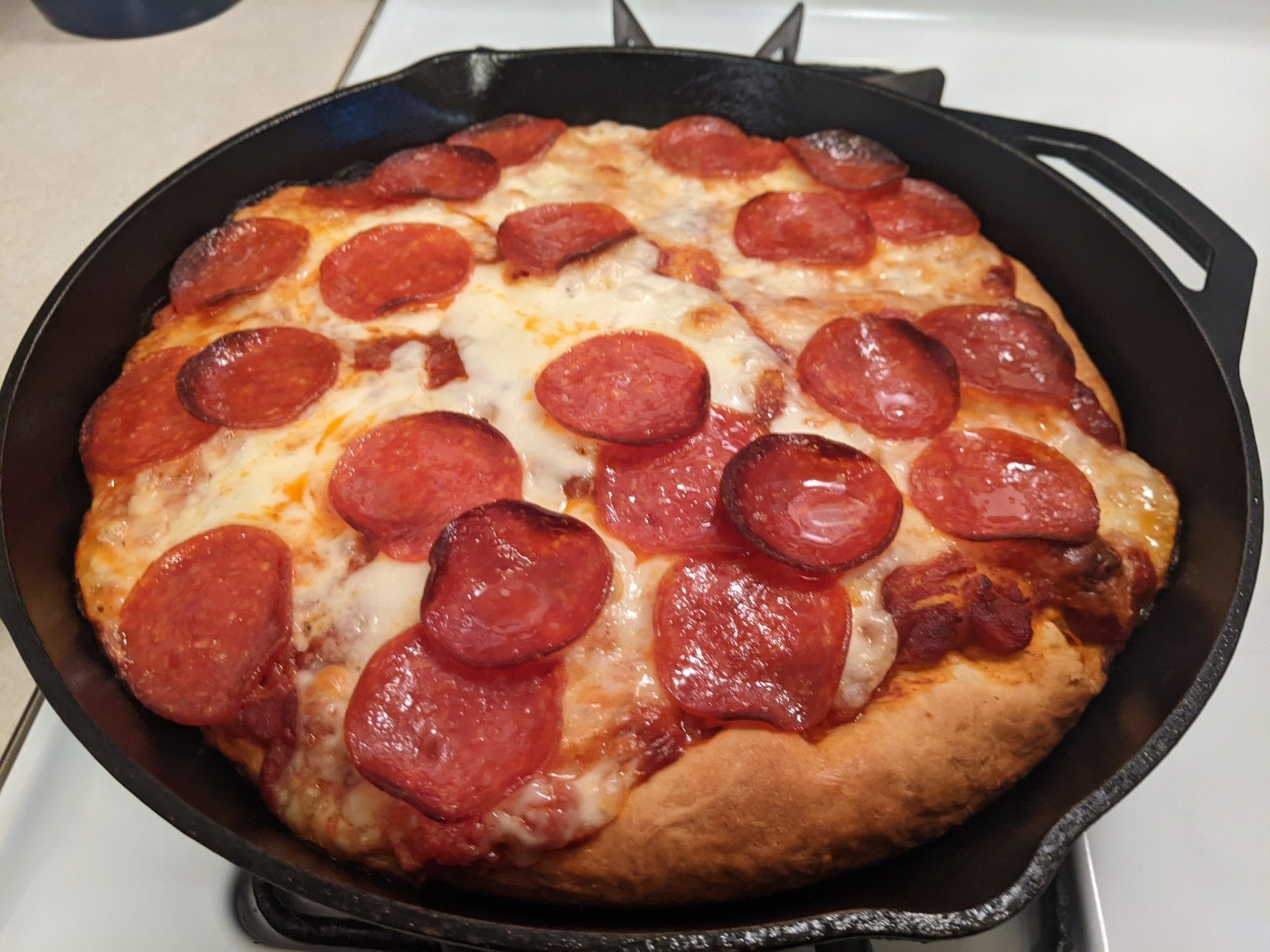 A second pan pizza in a cast iron pan, this one is topped with cheese and pepperoni