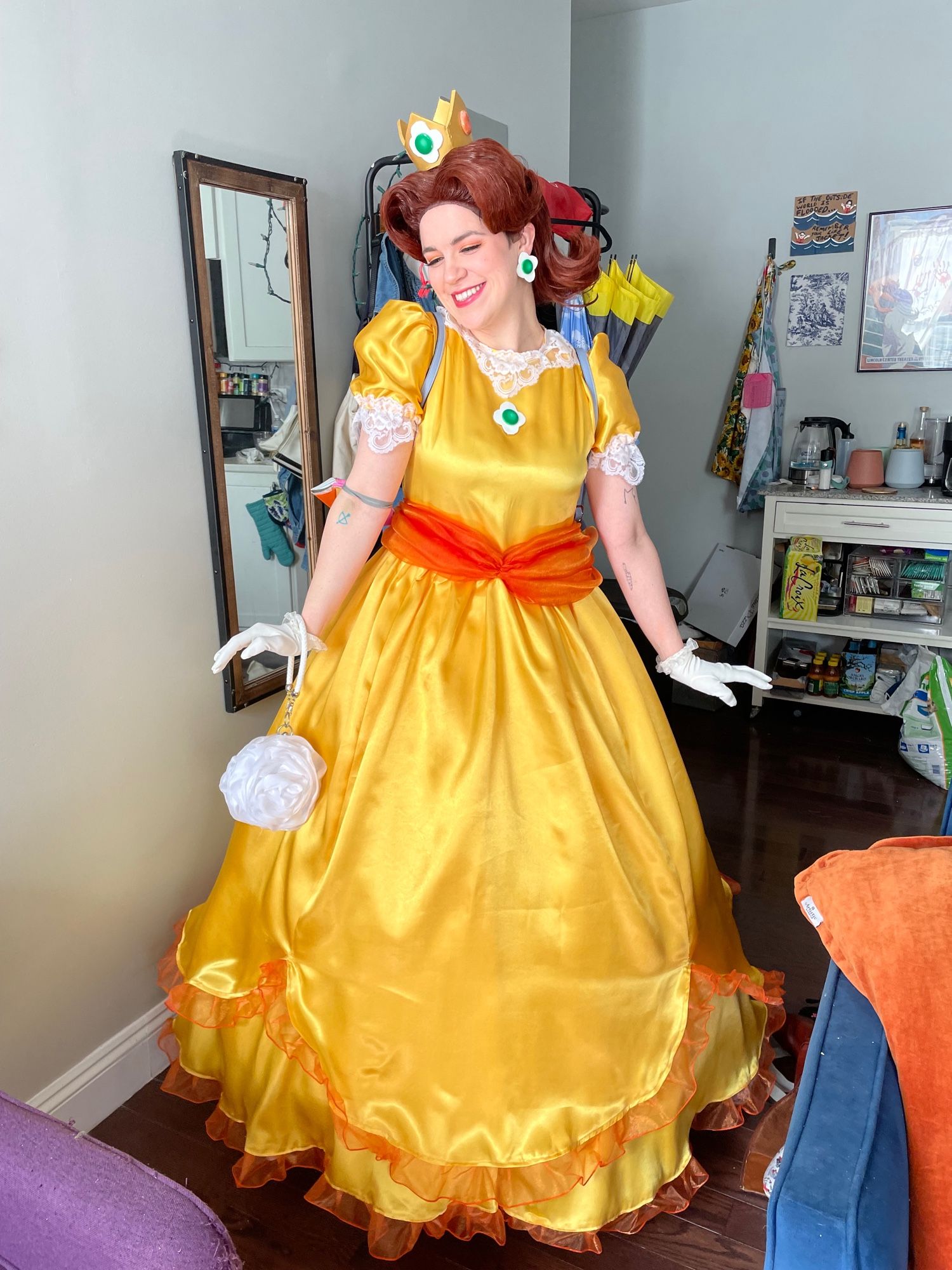 Claire in a Princess Daisy cosplay smiling & looking down to the right.