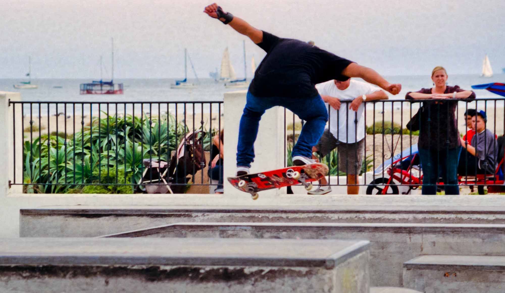 Skaters and bikers enjoying a skate-park at the beach on cloudy summer day. Shot on film. ~ Ventura, California