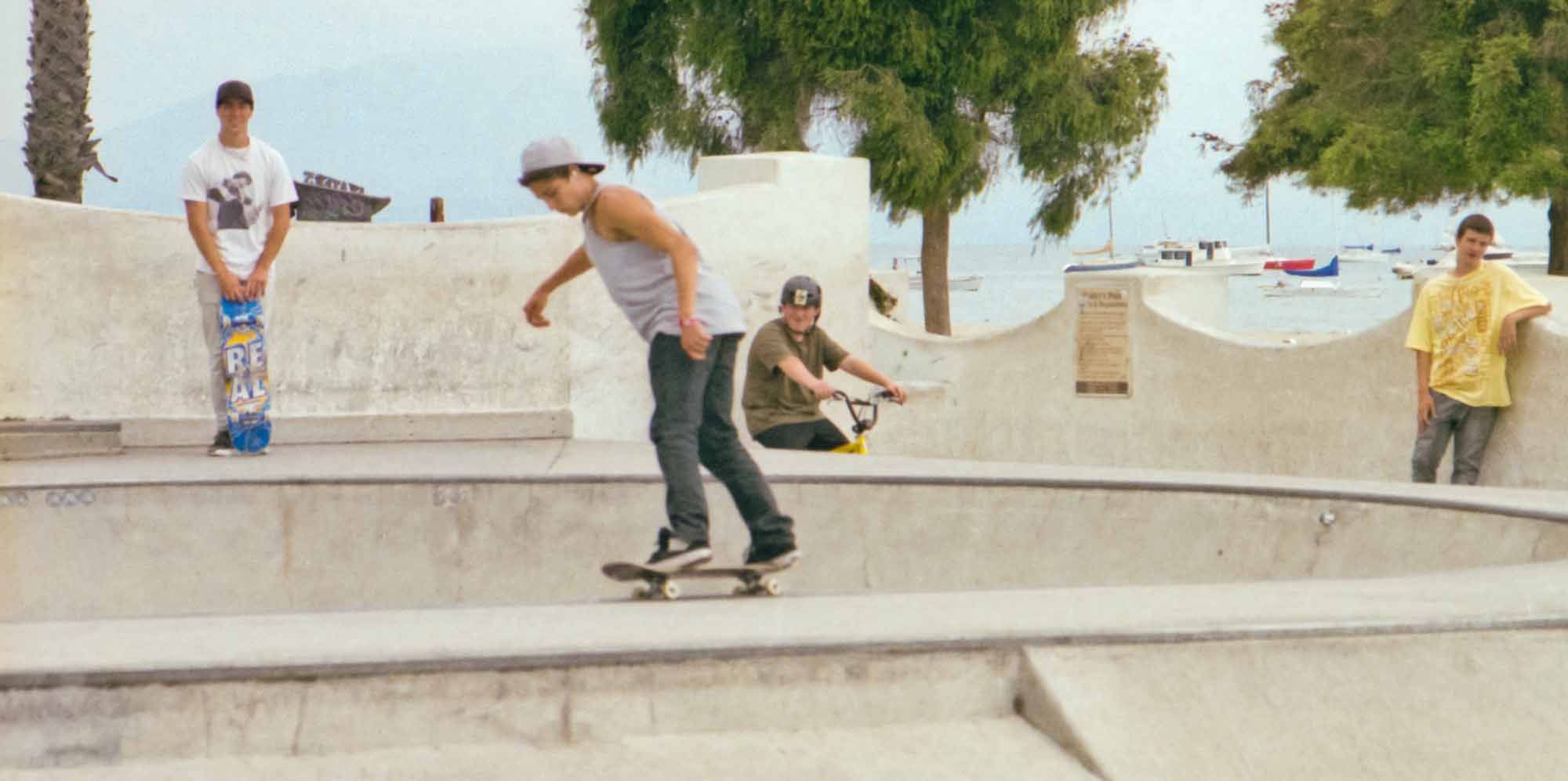 Skaters and bikers enjoying a skate-park at the beach on cloudy summer day. Shot on film. ~ Ventura, California