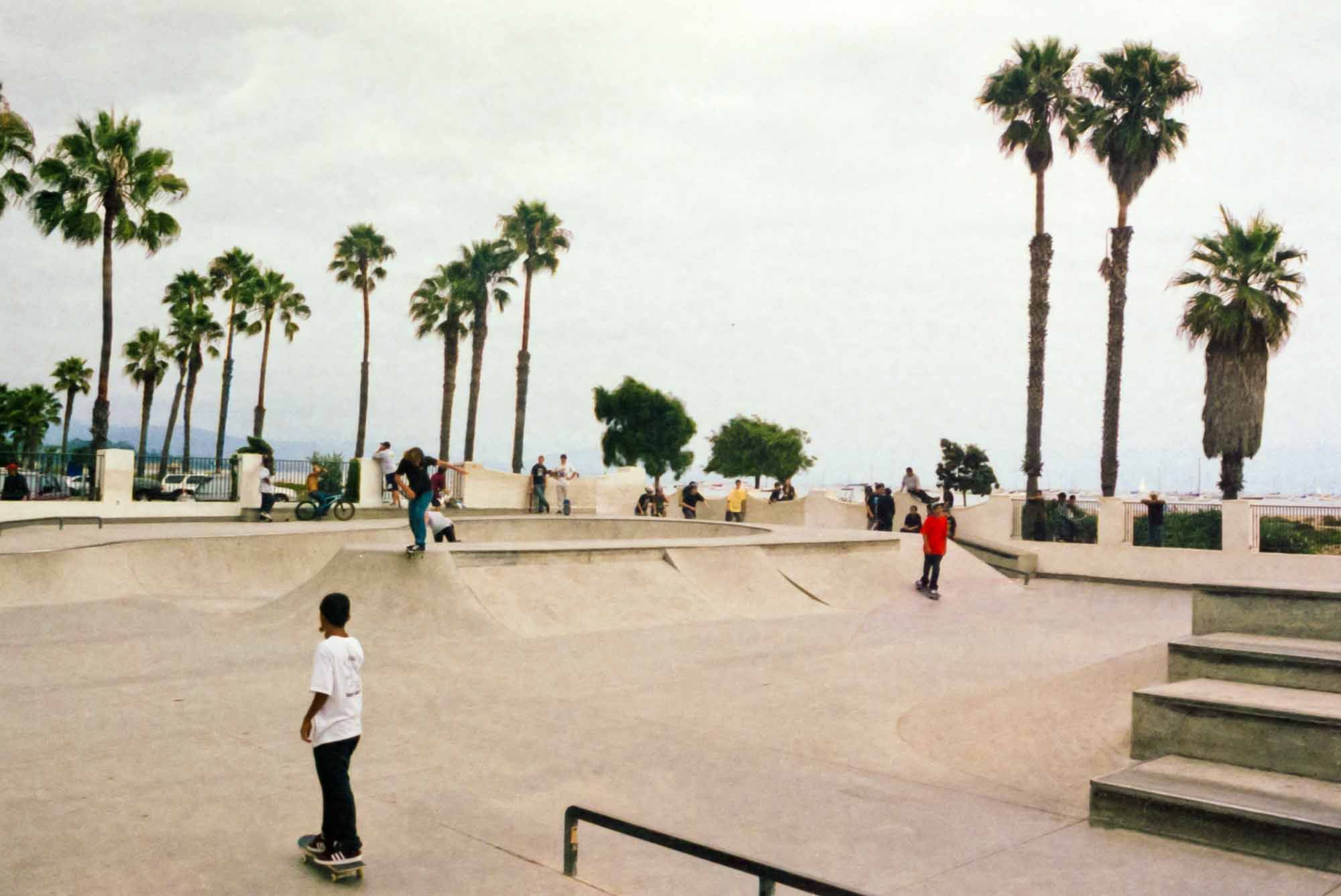 Skaters and bikers enjoying a skate-park at the beach on cloudy summer day. Shot on film. ~ Ventura, California