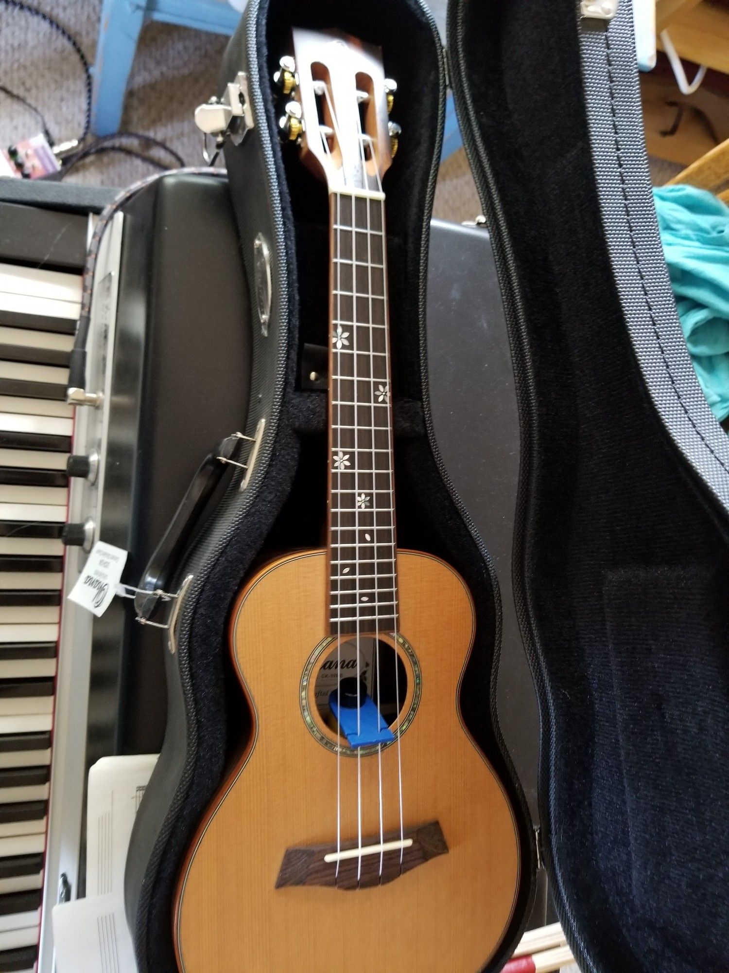 My new concert size cedar ukulele in a hard case resting on a Fender Rhodes piano