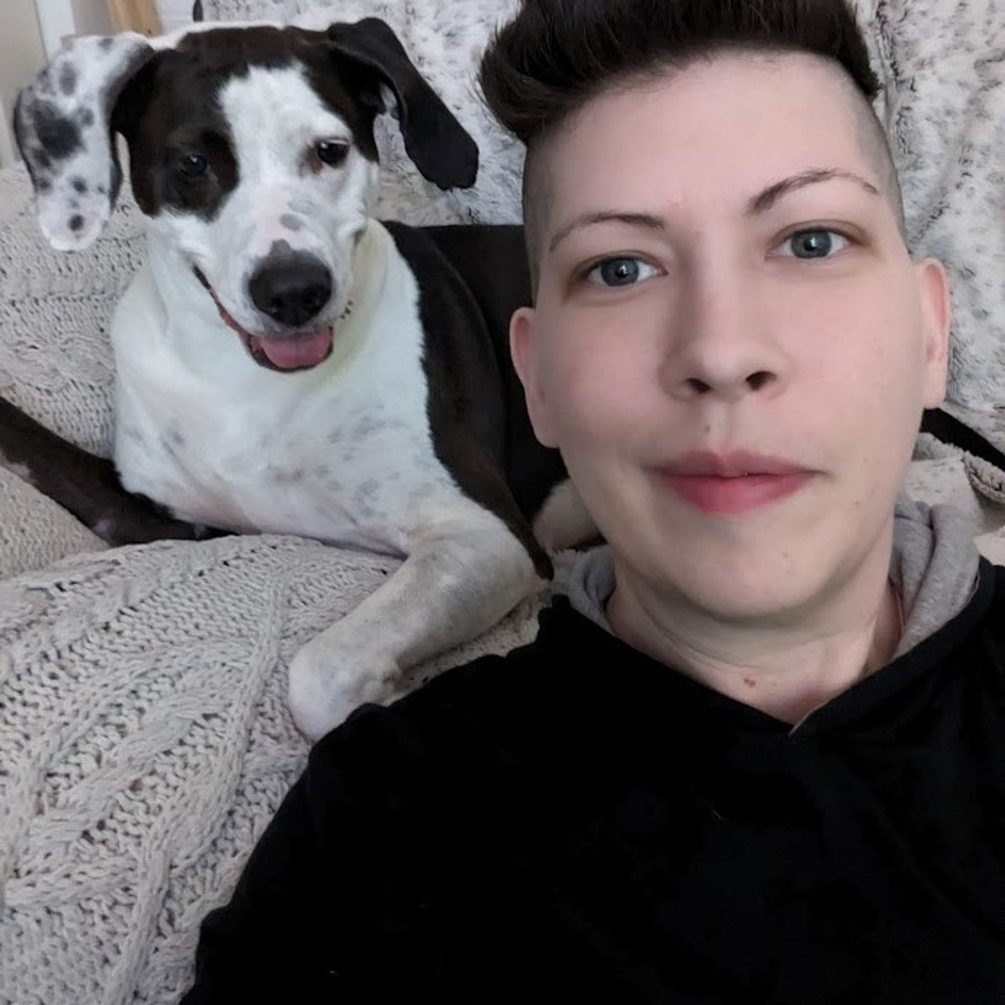 Wylder, a 42 year old trans person (he/them), and their dog Tasha, a black and white pitt-foxhound mix. Both are smiling. Pic almost 2 years old now.