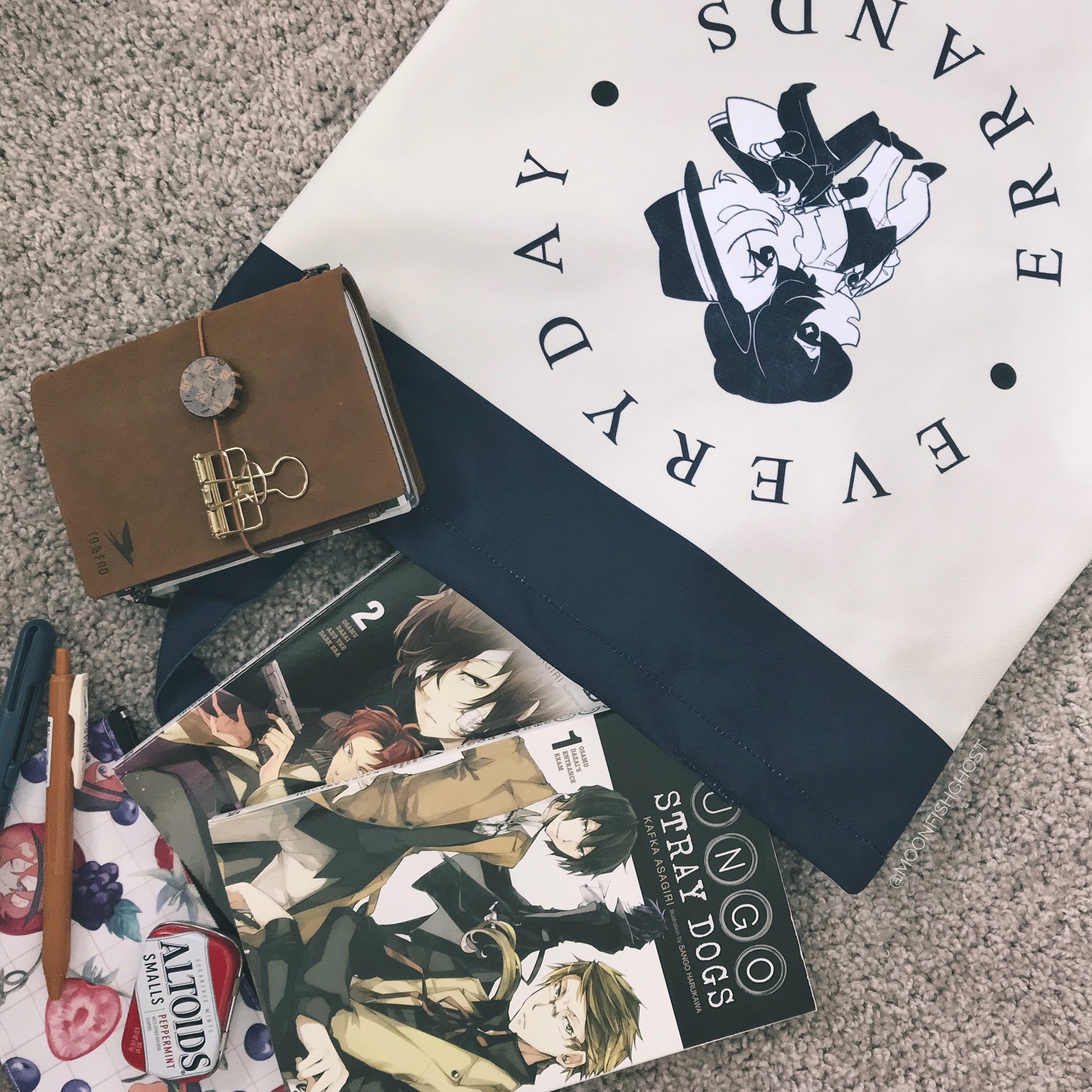 A soukoku inspired tote bag carrying lots of items such as books and pen pouches.