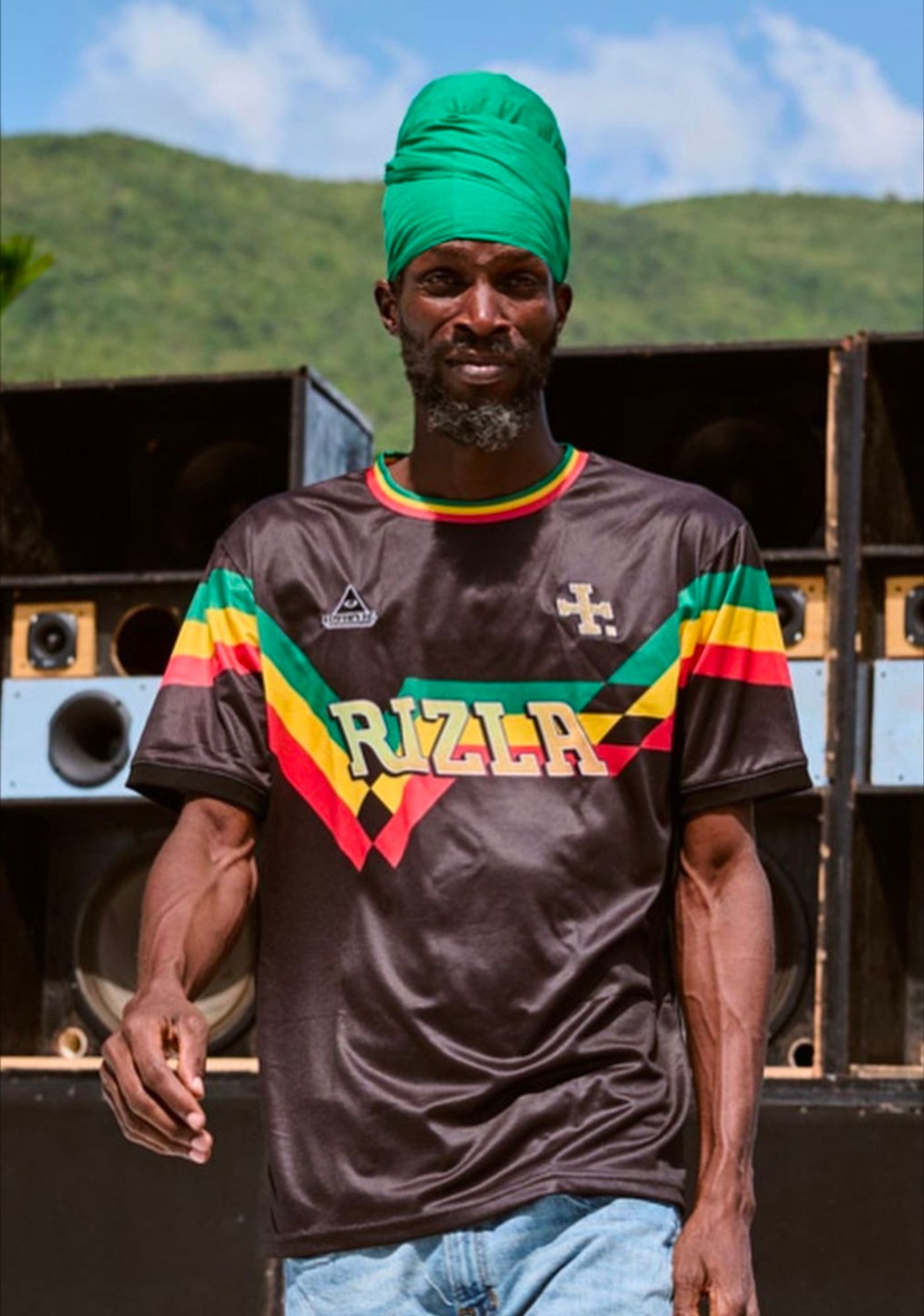 Rastafarian man wearing black football kit with Rizla branding, outside in sunny weather