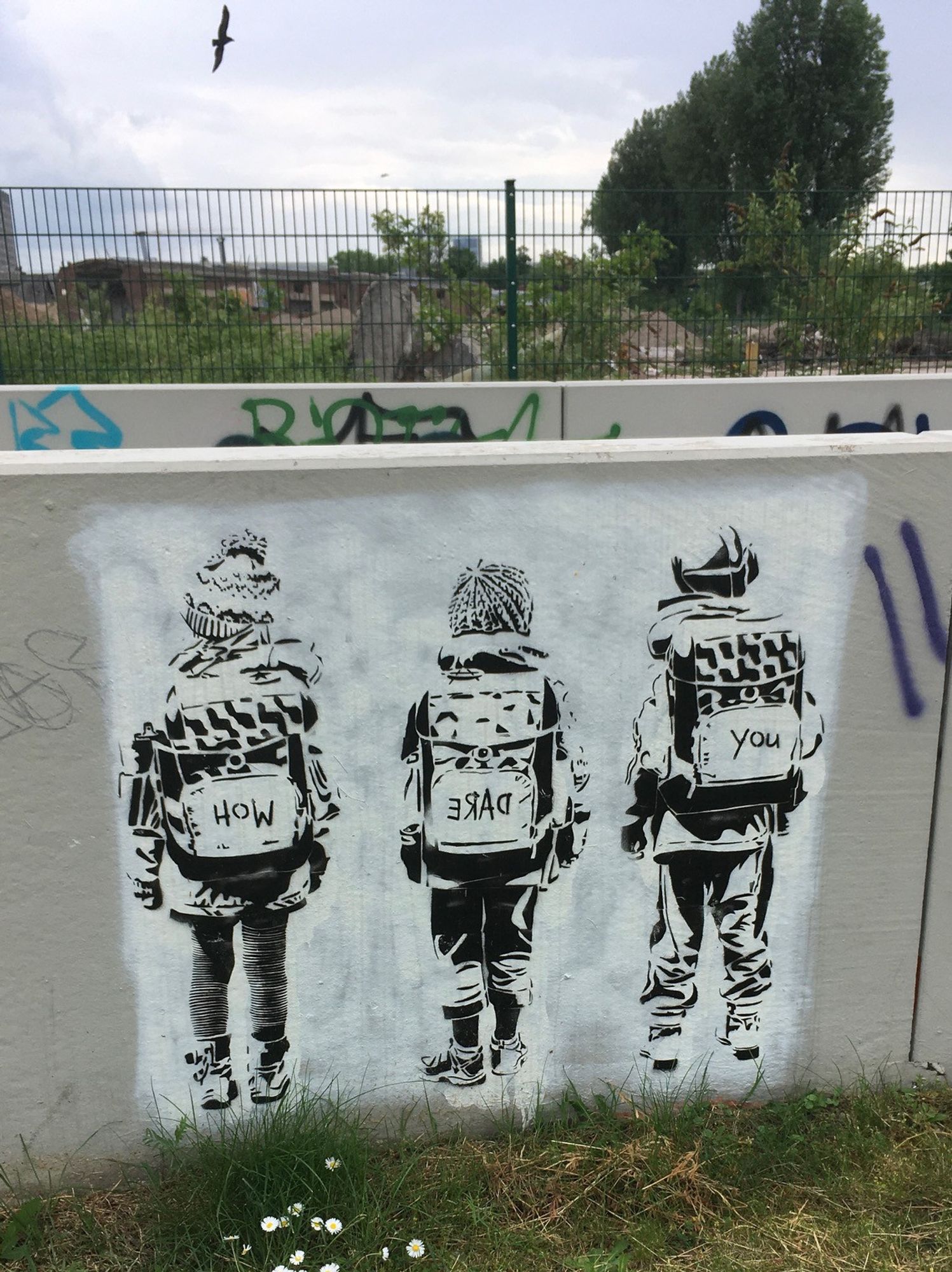 Stencil, schwarz auf weißem Grund: drei Kinder mit Mützen und Rücksäcken sind von hinten zu sehen. Auf den Rucksäcken steht jeweils ein Wort, how - dare - you.