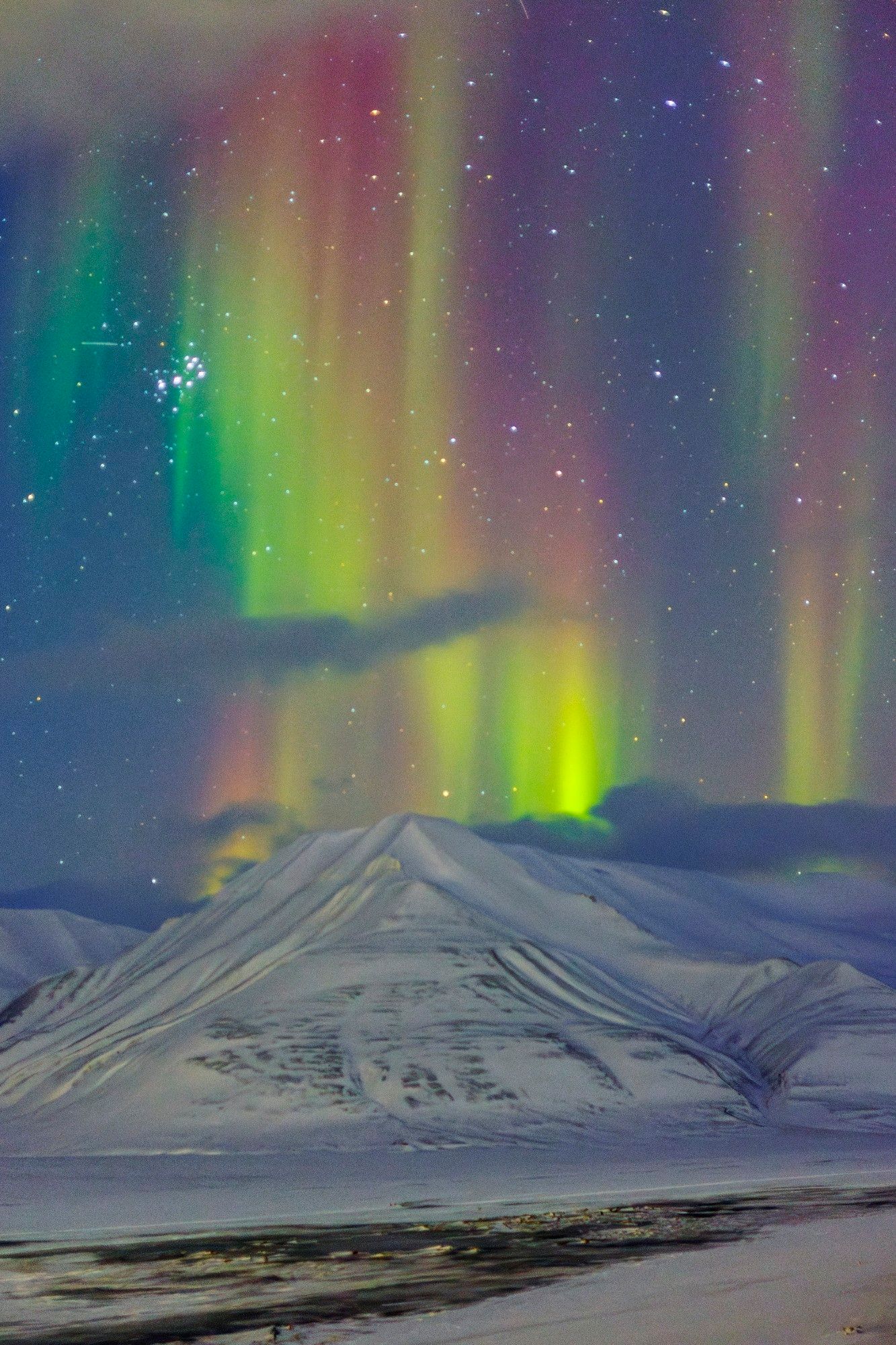 The aurora borealis visible over a snow covered mountain