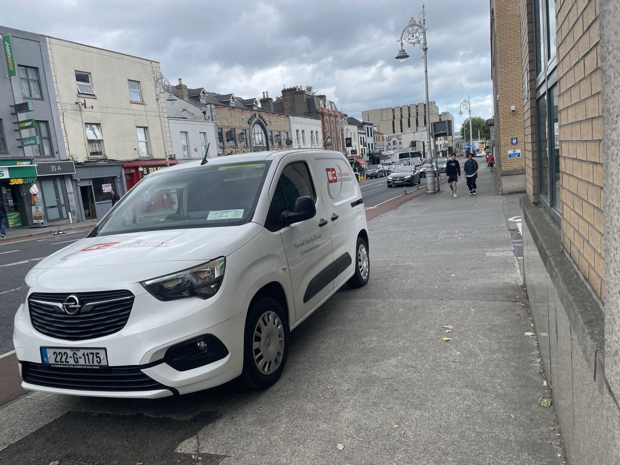 Parkgate St, Dublin 8 - a small white Opel van branded 'Colin Burke Fire and Security Division' is parked entirely on the footpath