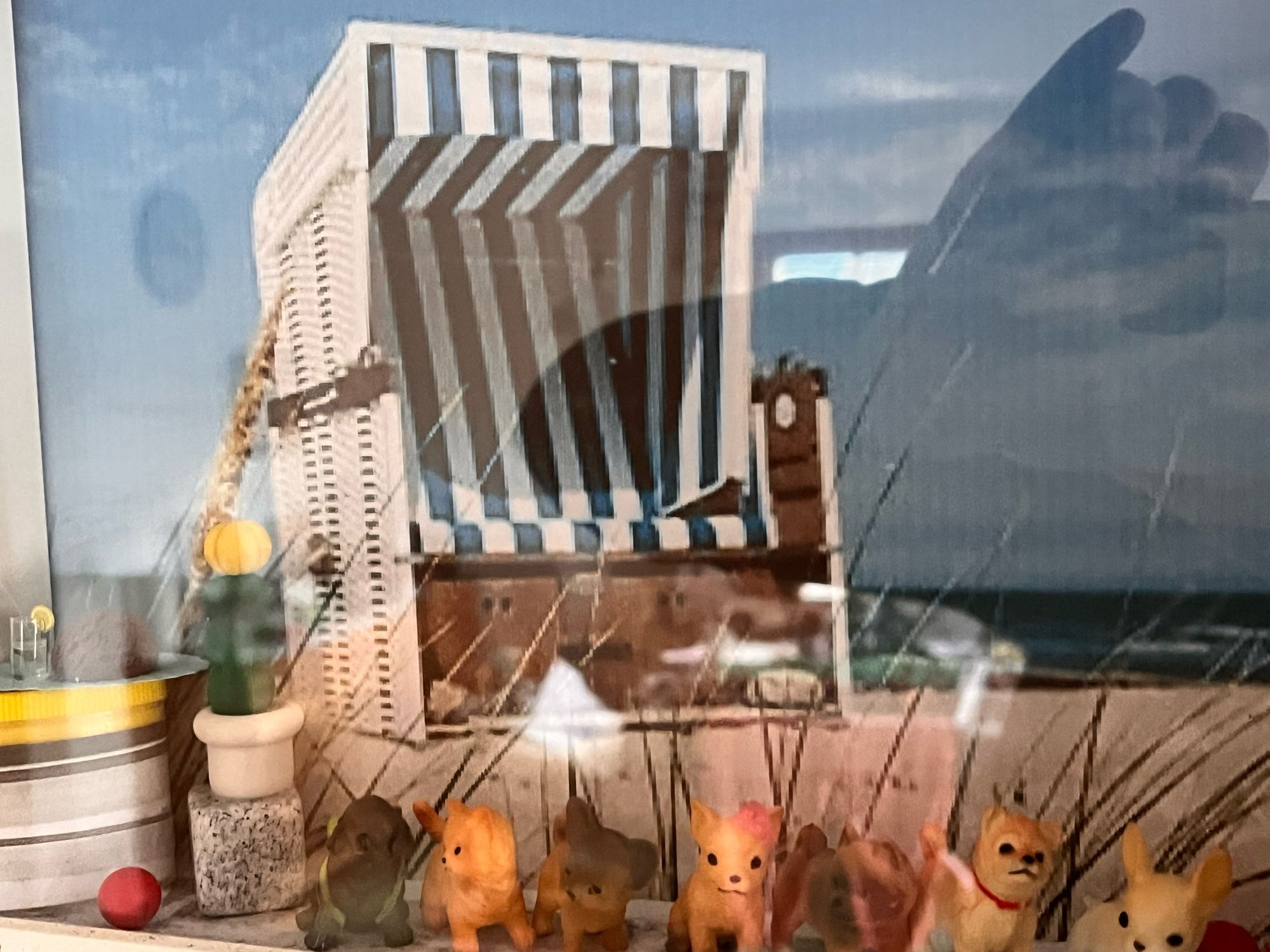 Foto eines Dioramas mit Strandszene. Strandkorb, Kaktus, mehrere kleine Hundefiguren und eine Katzenfigur