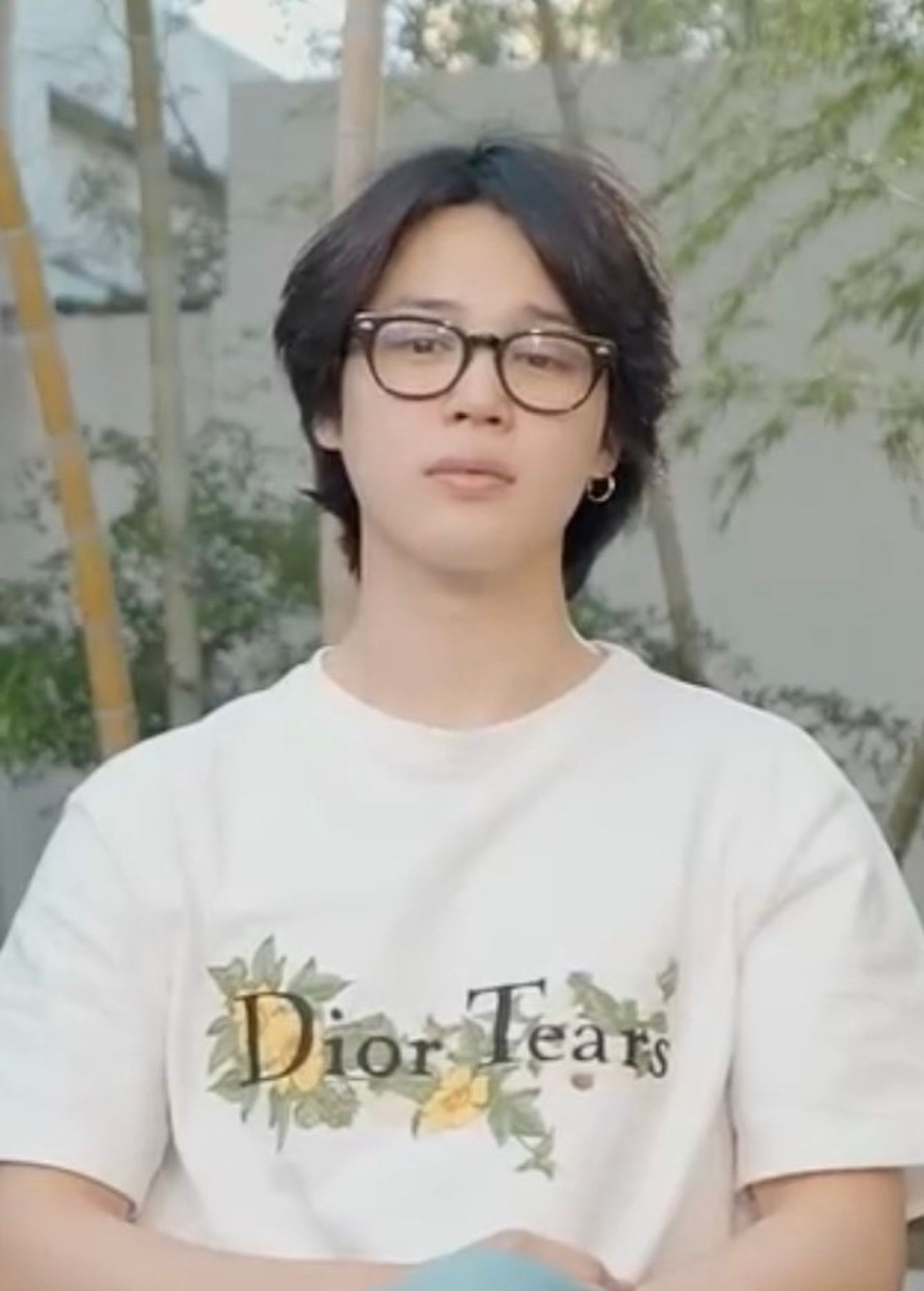 Jimin with a white Dior tee. Long thick black hair separated in the middle and black glasses