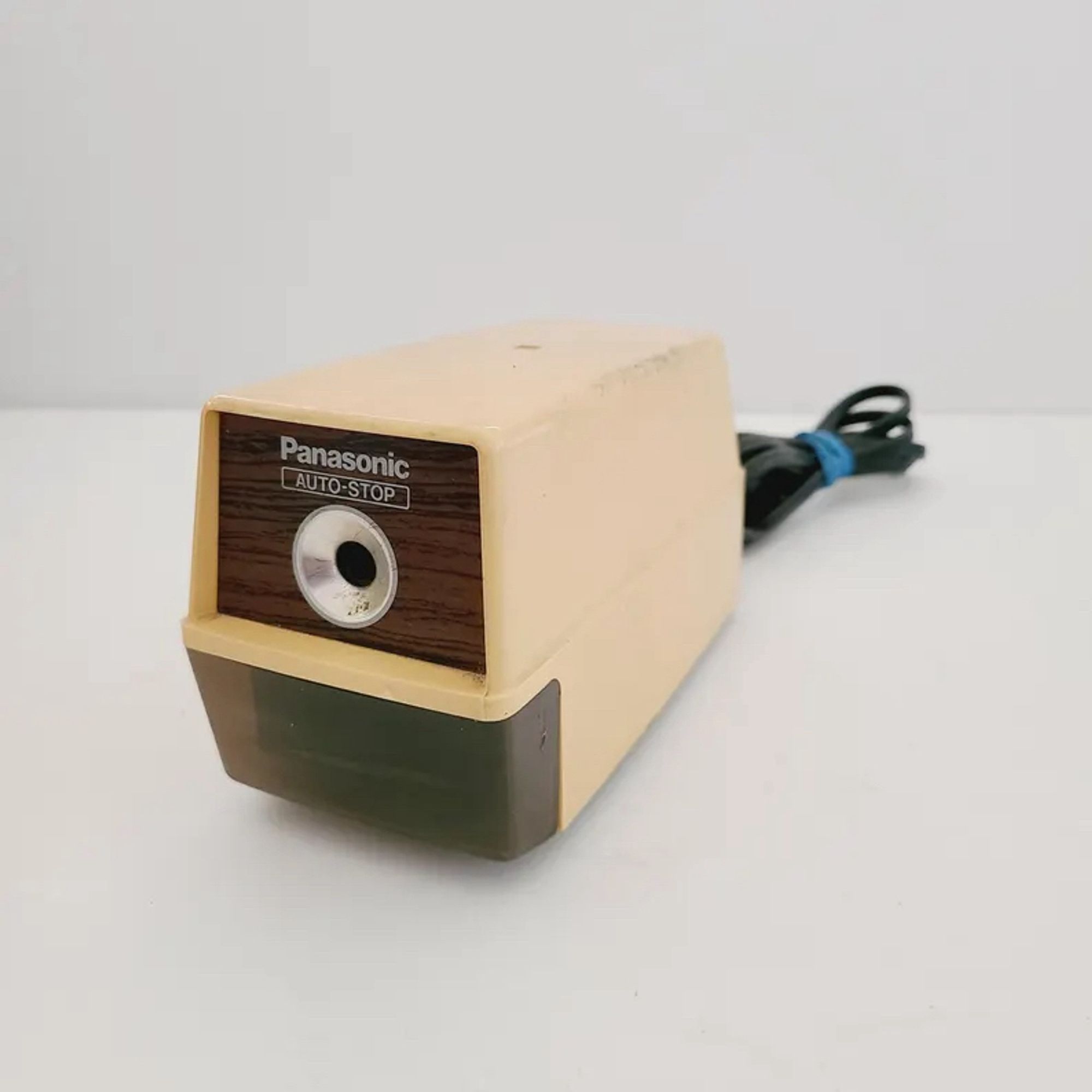 A cream and brown colored electric pencil sharpener