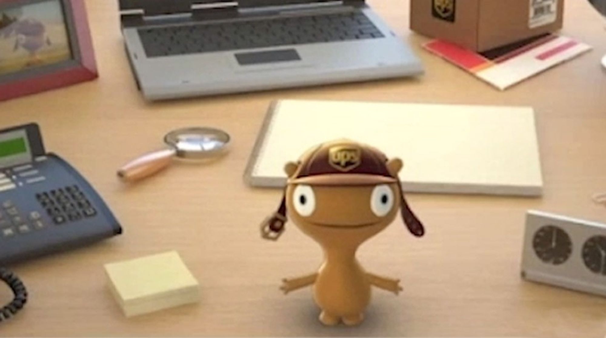 The UPS mascot named "Widget". It is mustard coloured. Its head is large and has a large amount of space between its big eyes and a wide smile, giving it a blank stare. Its arms are extended on either side and it is wearing a UPS cap with small nub-ears poking out.