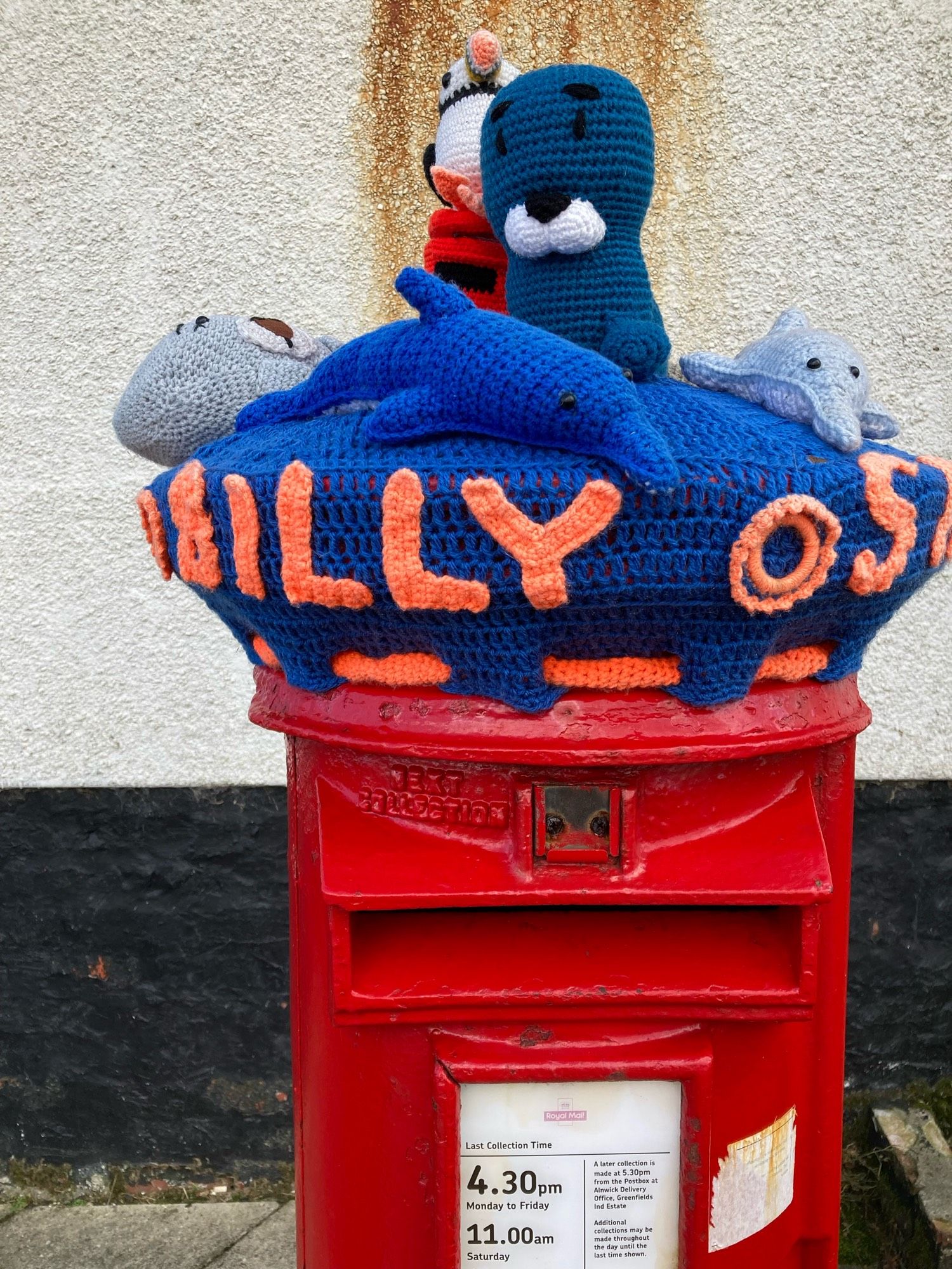 Royal Mail post box with knitted topper including seal, puffin, dolphin and octopus.