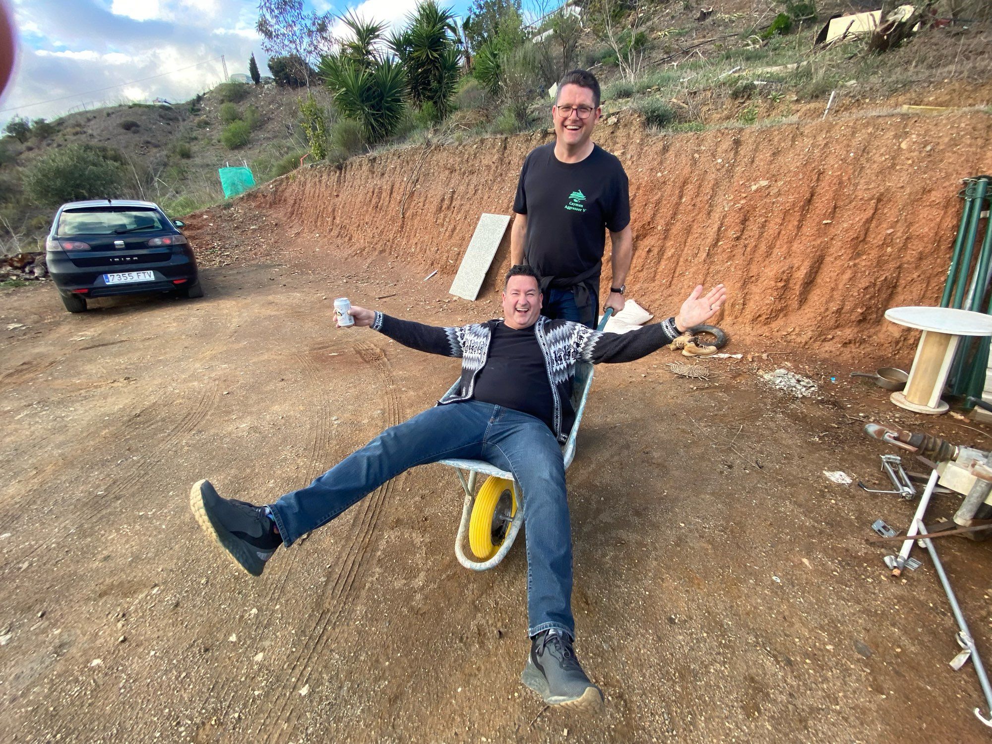 I am reclining in a wheelbarrow that my friend is pushing on a hillside in Spain