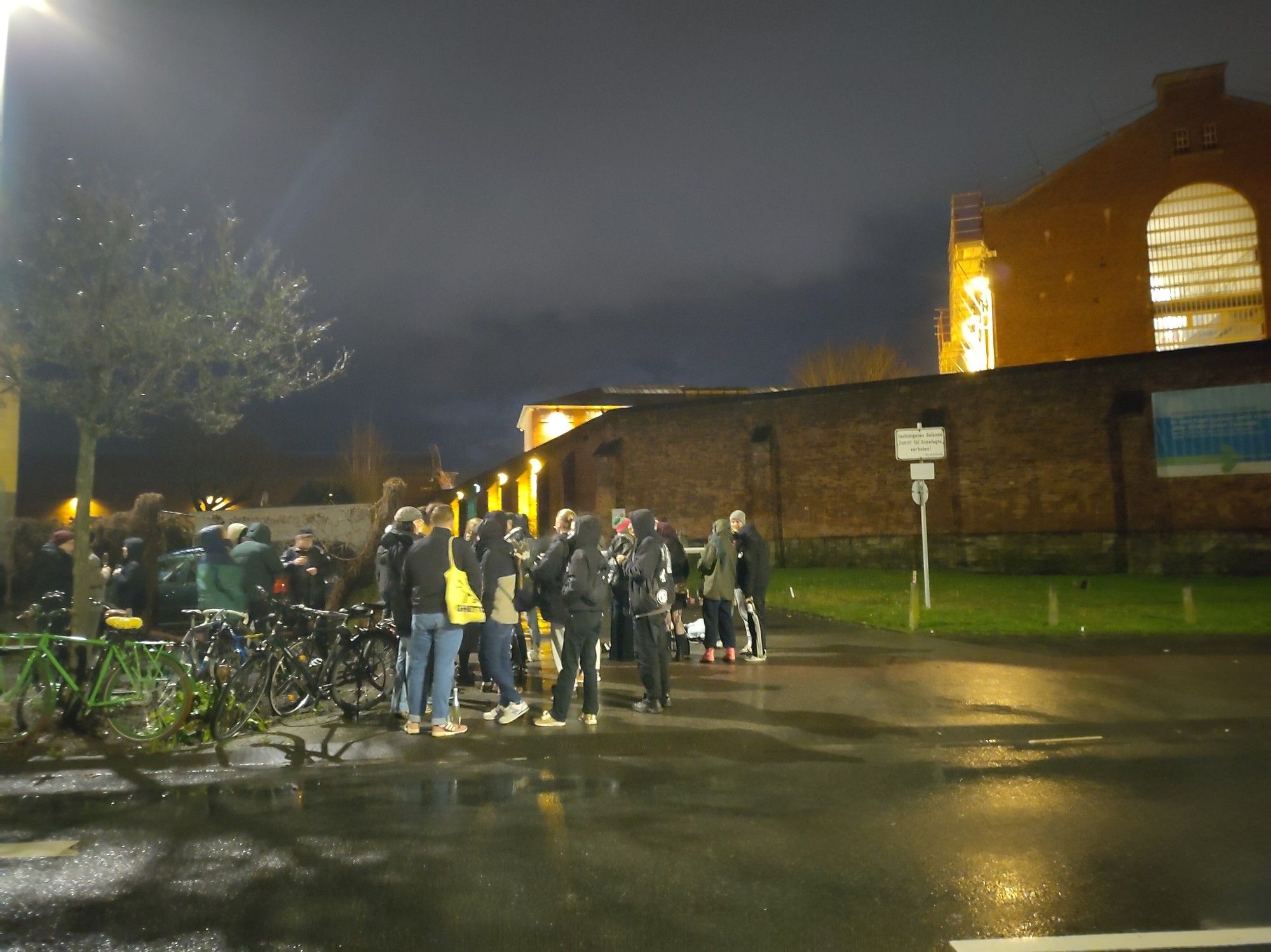 Mehrere Dutzend Menschen stehen in der Dunkelheit vor der Mauer der JVA Münster.