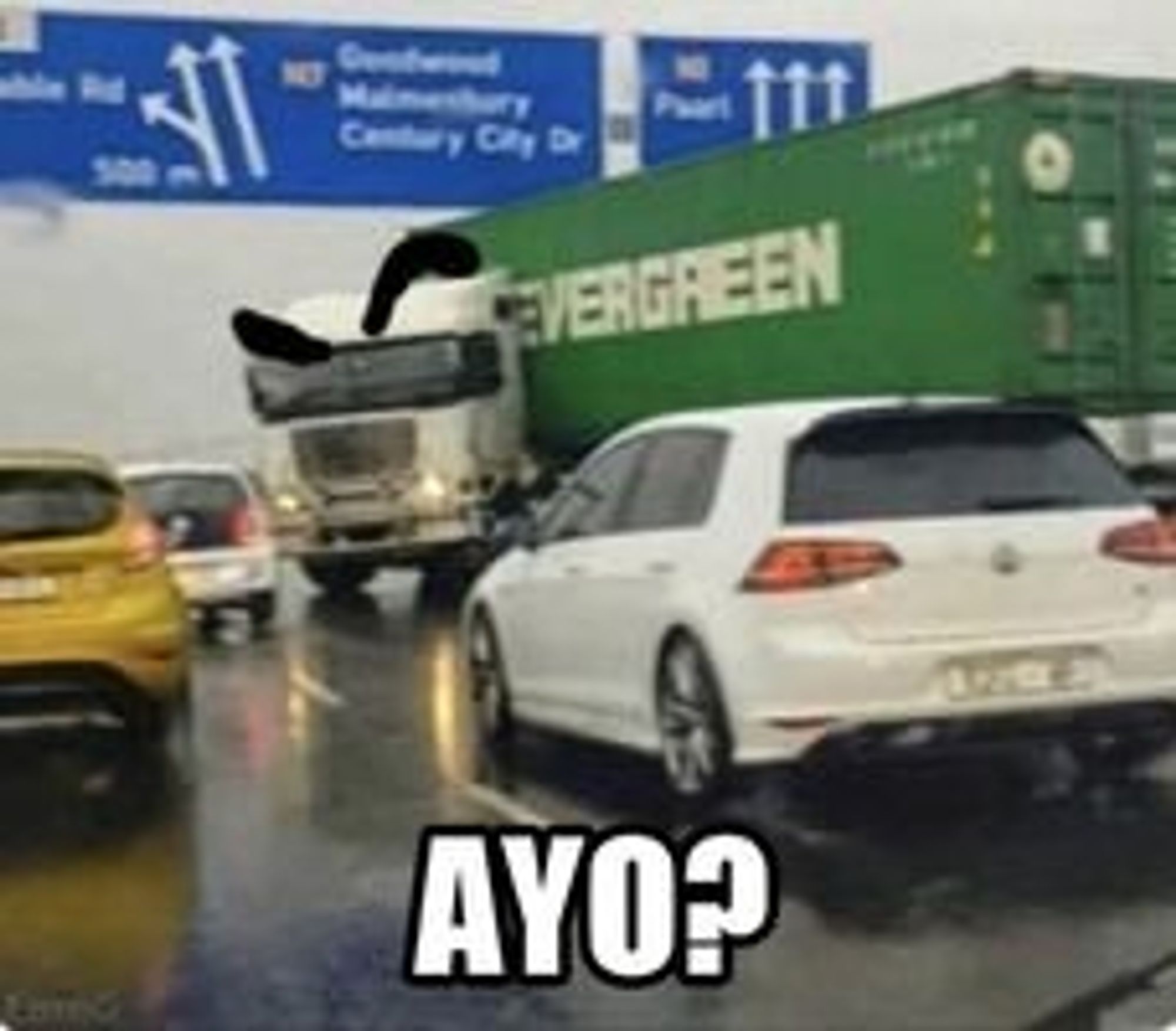 A tractor trailer is jack knifed on a highway, with the tractor facing stopped on coming traffic. Raised eyebrows are painted onto the tractor (post edit effect) with the bottom text reading "Ayo?", implying a state of disbelief. 