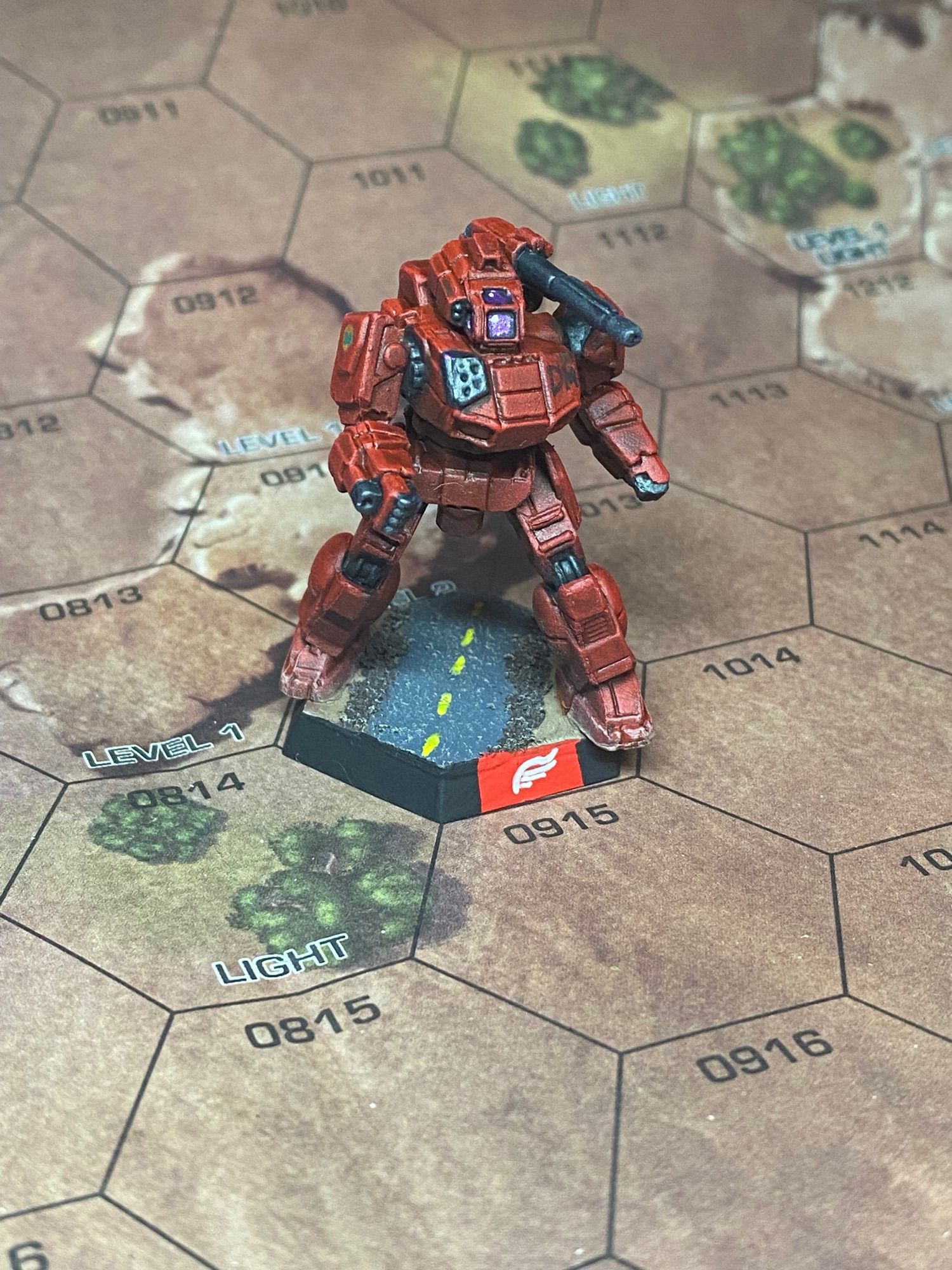 A red mech on a desert road with “DM” emblazoned on the chest