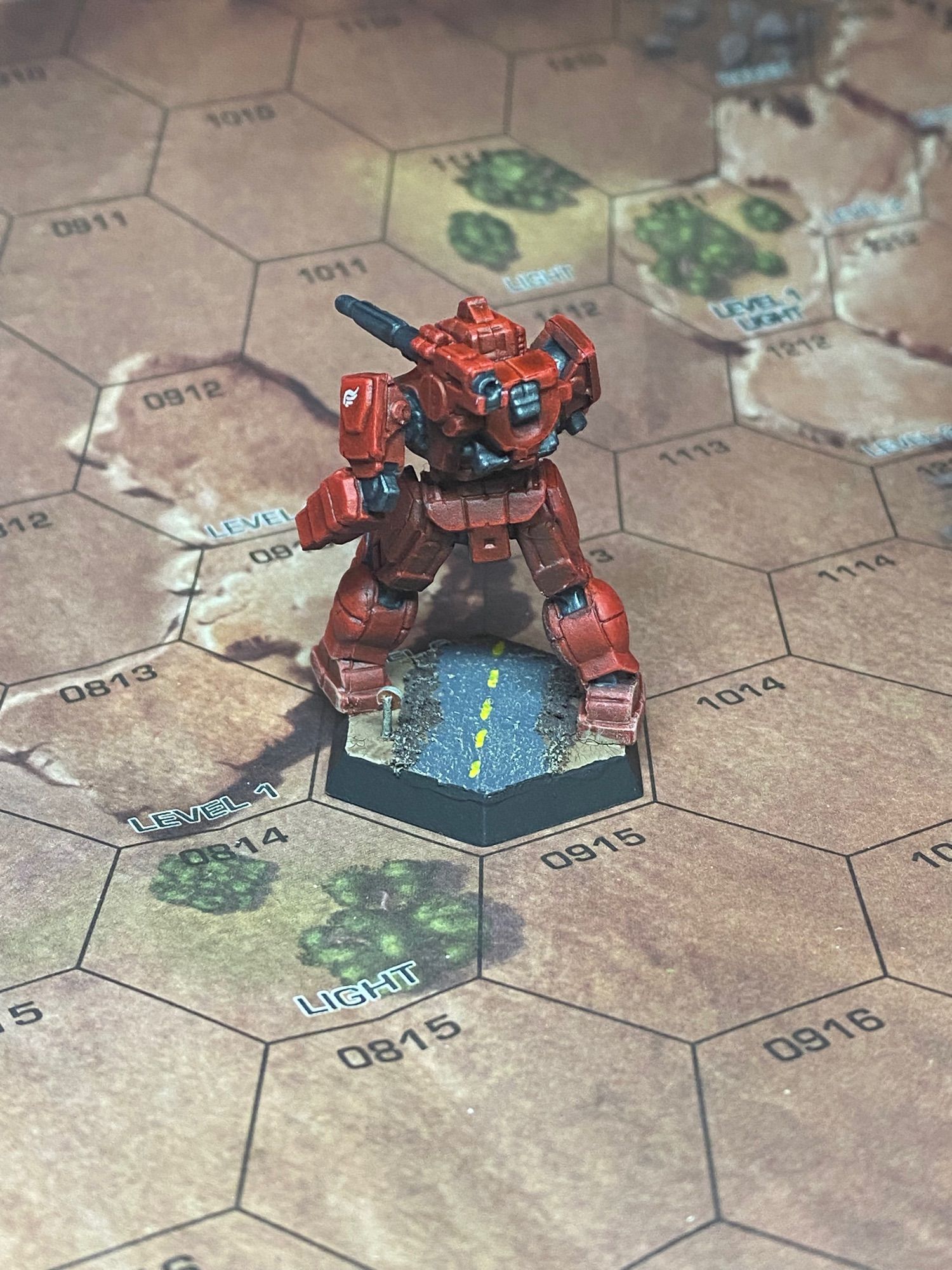 A red mech on a desert road facing away from the camera