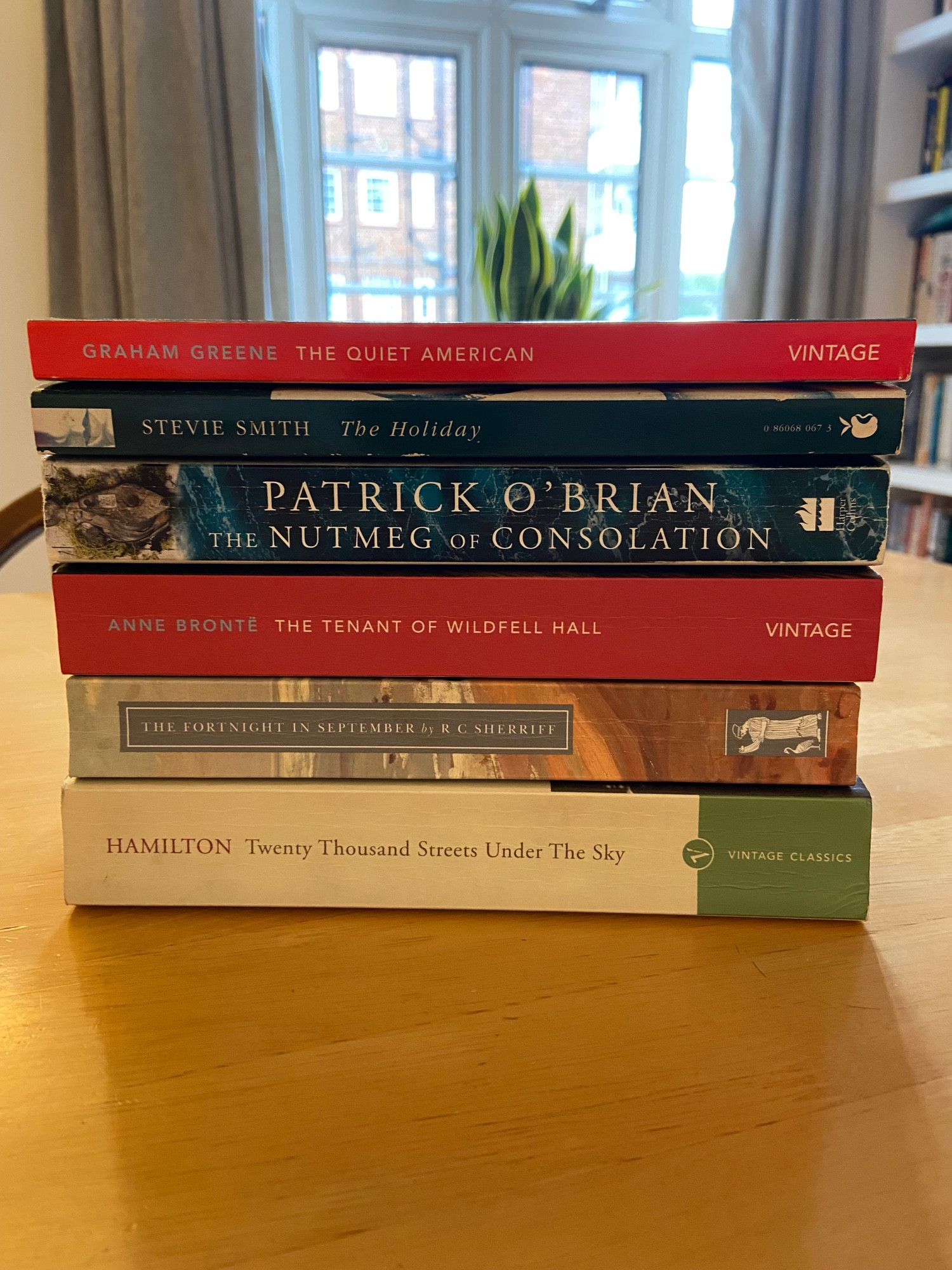 A stack of books including titles by Graham Greene, Anne Brontë, Stevie Smith, Patrick O’Brian, RC Sherriff and Patrick Hamilton.