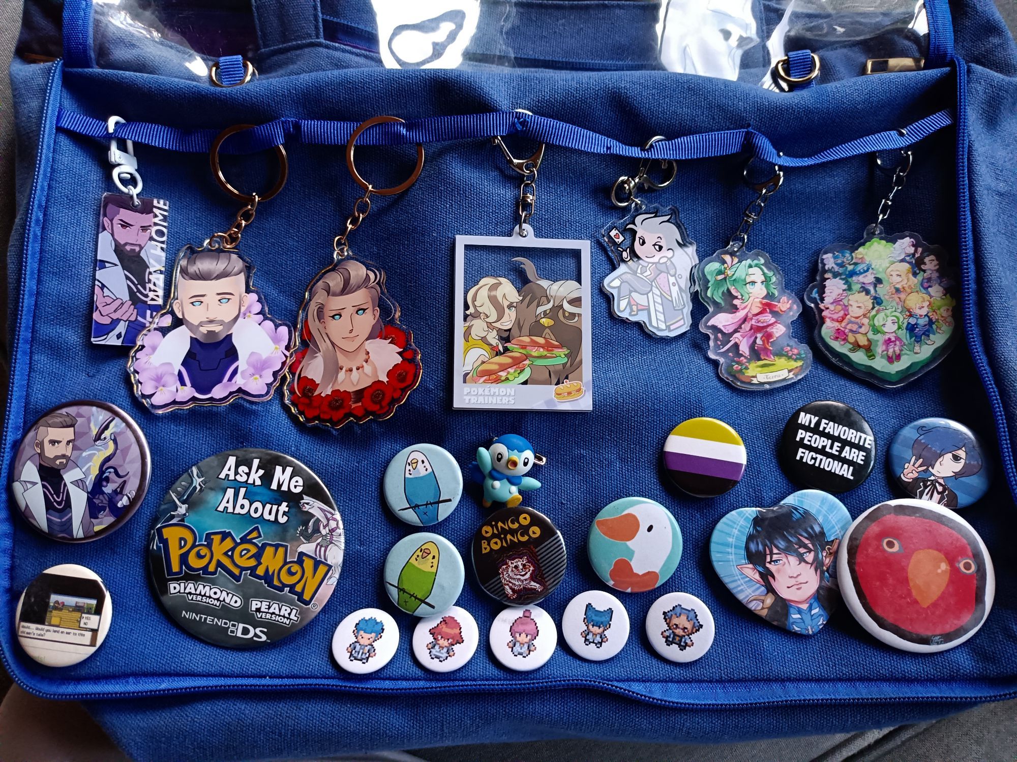 Itabag with keychains from Pokémon SV and Final Fantasy 6, with pins from those plus Pokémon DPPt, Persona 3, Untitled Goose Game, and Final Fantasy XIV, plus Gumi the Red Birb, Oingo Boingo's first album cover, and parakeets