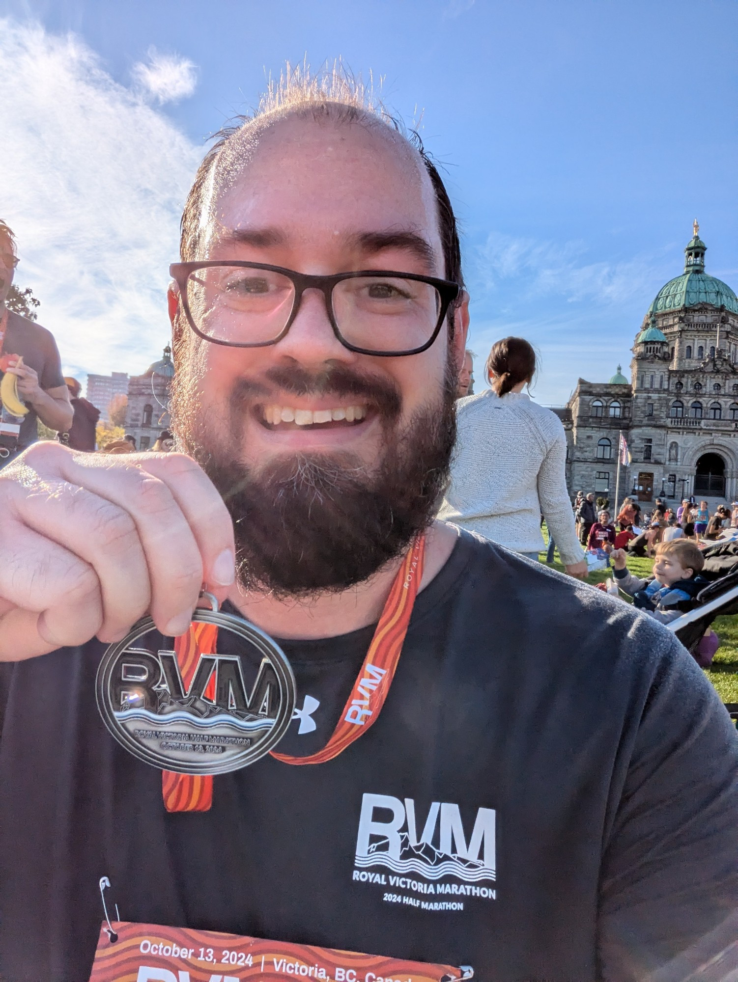 Selfie in front of the BC Parliament Buildings while I hold up my Royal Victoria Marathon finisher's medal.