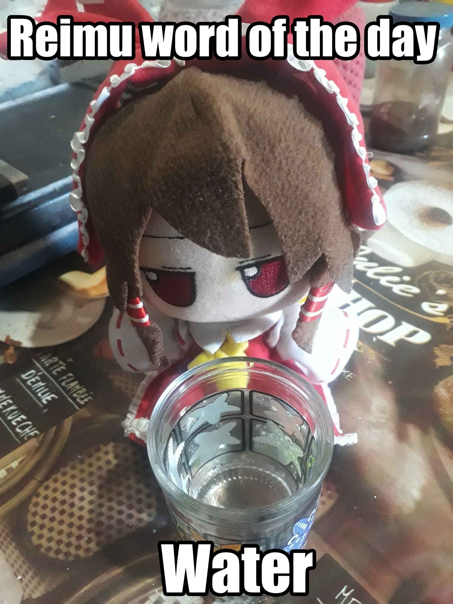 Reimu Hakurei fumo, sitting at a table with a lining, the pattern on this lining has donuts and coffee cups, in front of her is a glass cup with drawings of starfish with water inside