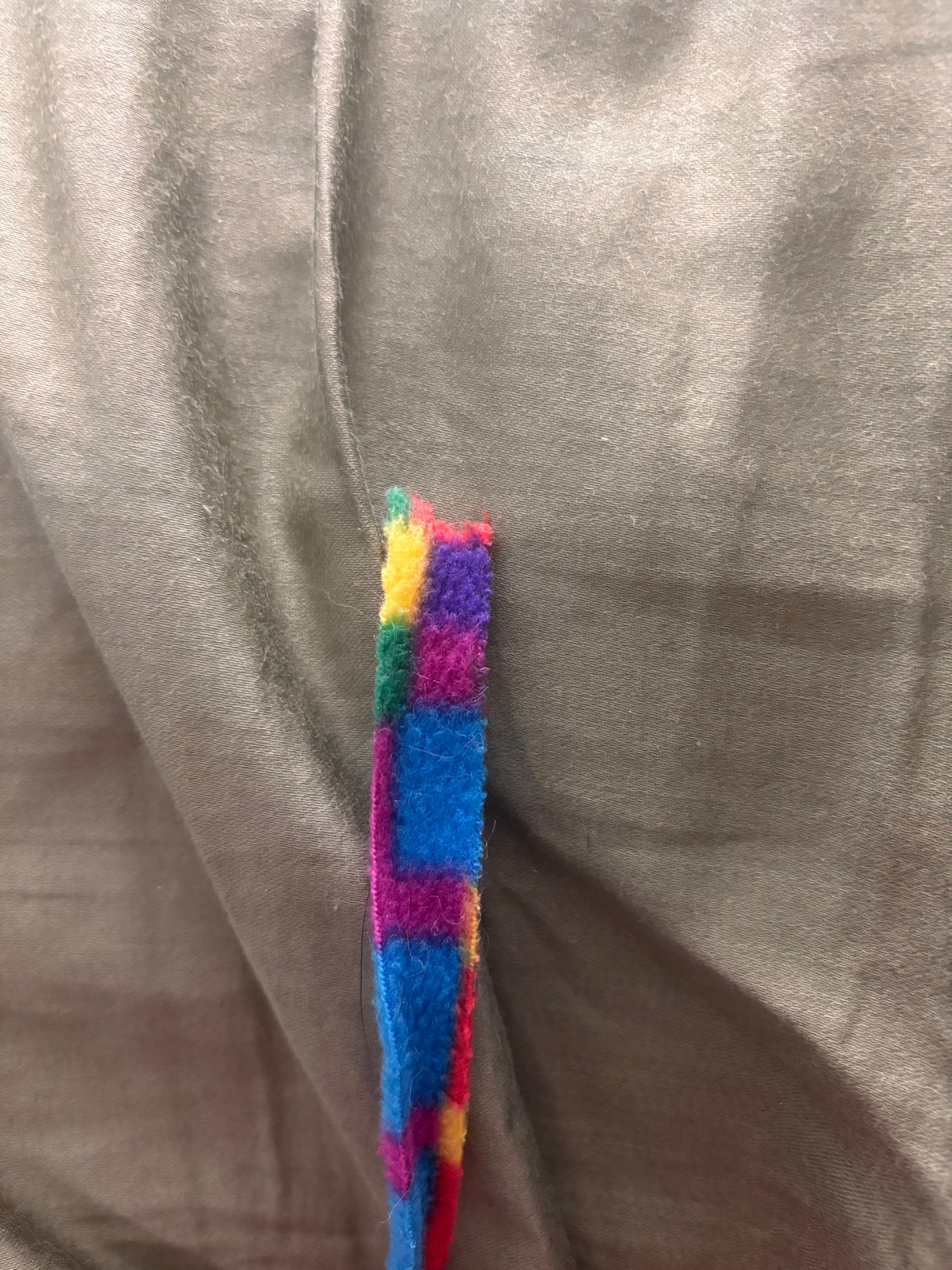 a close up of a felt ribbon cat toy. the tip has been chewed up