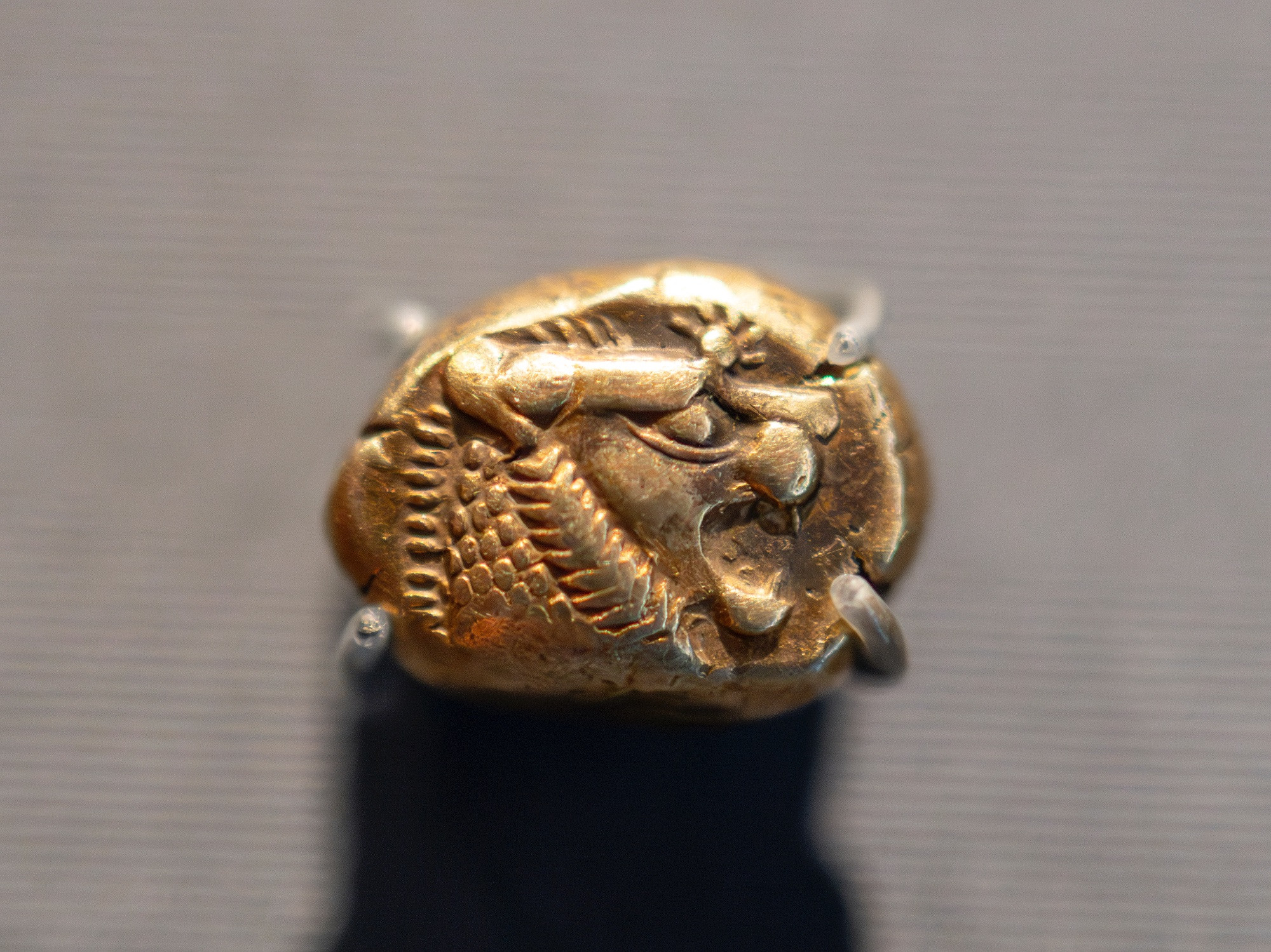 From the ancient kingdom of Lydia, this electrum (a naturally occurring alloy of gold and silver) coin is no bigger than a fingernail. Worth 1/3 stater, it represents the beginning of coinage in the world, just edging out coinage production in India and China. Dated to about 600 BCE, it would have been made during the reign of King Alyattes (r. 619-560 BCE), under whose rule the first coins were minted. It's no exaggeration to say that all subsequent coins - up through the modern day - are based on the Lydian stater.

The first Lydian staters were about the same size but blank. They rapidly gained decoration, and the lion featured on many of the denominations. This particular coin depicts a lion's head in profile, its mouth open in a roar, a sunburst symbol above. The lion was the symbol of Lydia's capital city of Sardis, where this coin was minted. A tiny bit of copper was added to the electrum blend in order for these coins to appear golden - electrum is naturally a whiter metal. King Croesus (r. 560-547 BCE), Alyattes' successor - yes, *that* Croesus - decided to improve upon the electrum coin by introducing highly pure gold and silver staters. These coins had the advantage of a more definite intrinsic value of their underlying metals, whereas electrum's worth was more difficult to calculate due to the mix of metals.

This particular coin was the most common fractional coin within this system, the third-stater, or trite, which — just as it sounds — was one-third the weight of the stater. Some sources have surmised that the value of a third-stater amounted to a month's subsistence; others have placed its monetary worth somewhat lower. In addition to thirds, there were also sixth-staters, twelfth-staters, as well as staters in fractions of 1/24, 1/48, and 1/96.

Trite, or third-stater, electrum, struck in Sardis, Lydia (part of modern-day Turkey), about 600-560 BCE.

Getty Villa Museum, on loan from the American Numismatic Society (1944.100.48851)