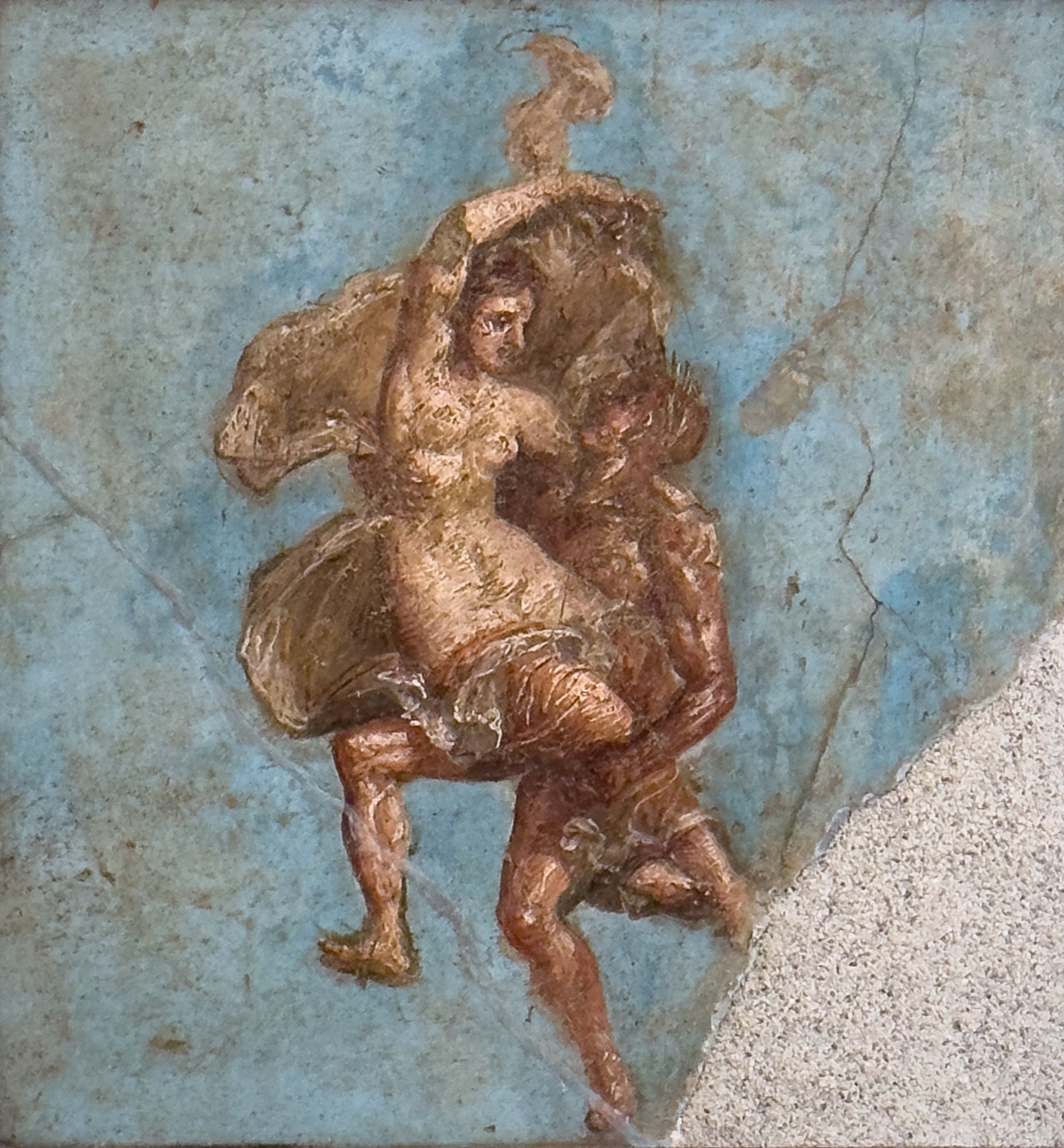 A naked young satyr with dark reddish-brown skin has his hands full of a pale nearly-naked maenad (female follower of Dionysus), her silken garment billowing around both of them. The background is a beautiful Egyptian blue.