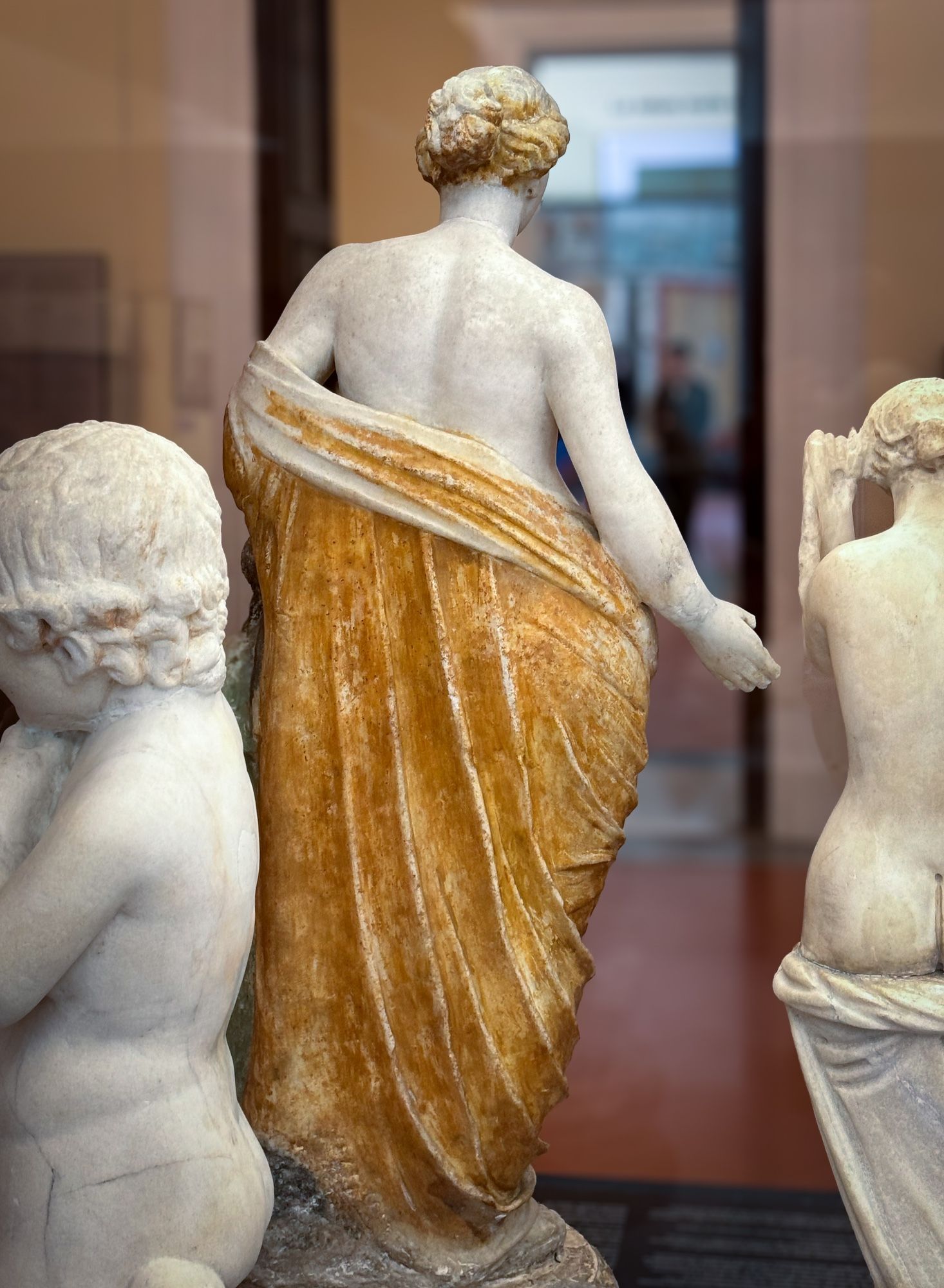 Rear of a statuette of Venus, her wrap - falling down her back - painted in a deep yellow-orange color, her hair painted yellow with orange shadows. 

Museo Archeologico Nazionale di Napoli (Naples National Archaeological Museum, inv. 109608)