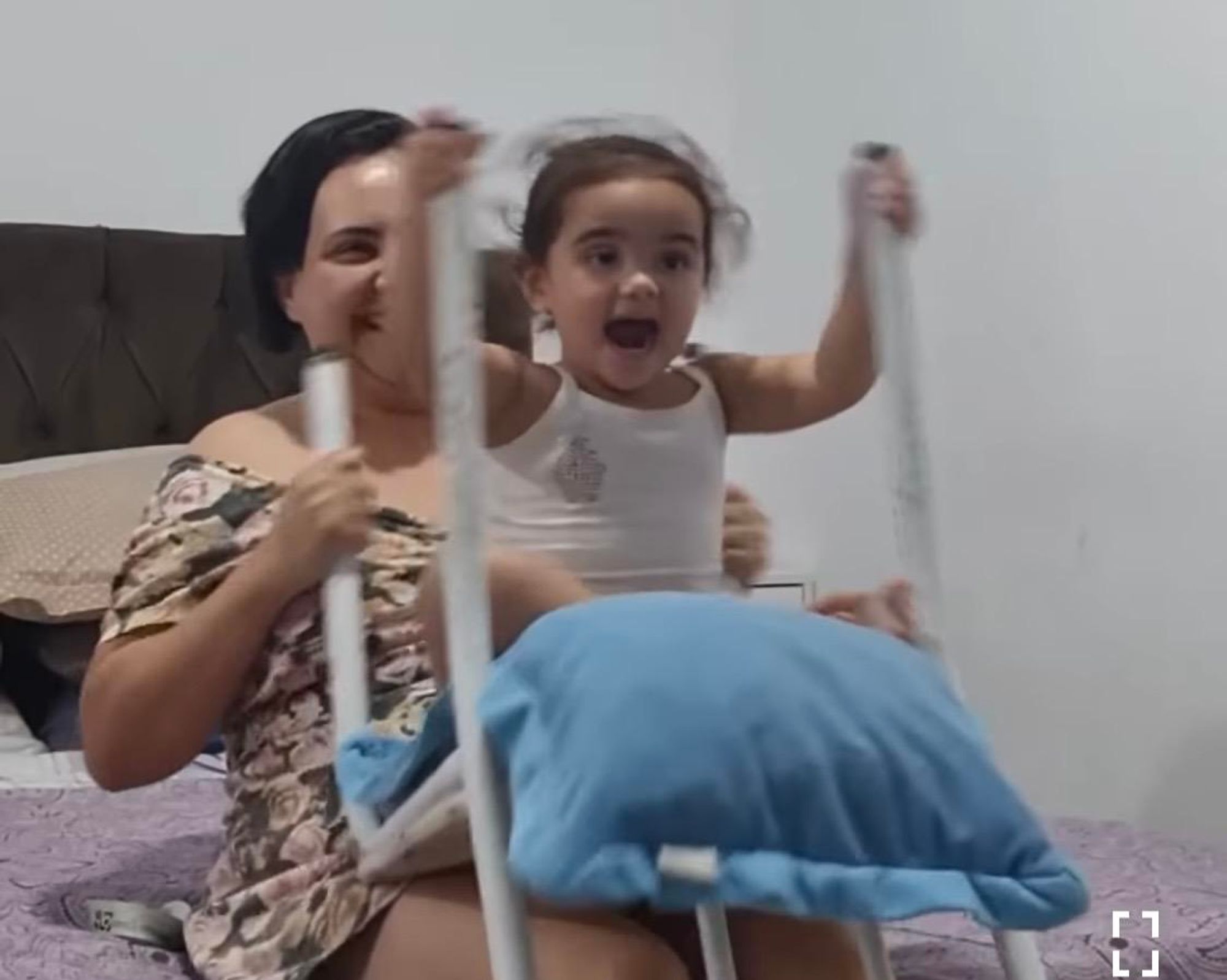 A mother simulates a rollercoaster ride for her child using an upside-down living room chair.