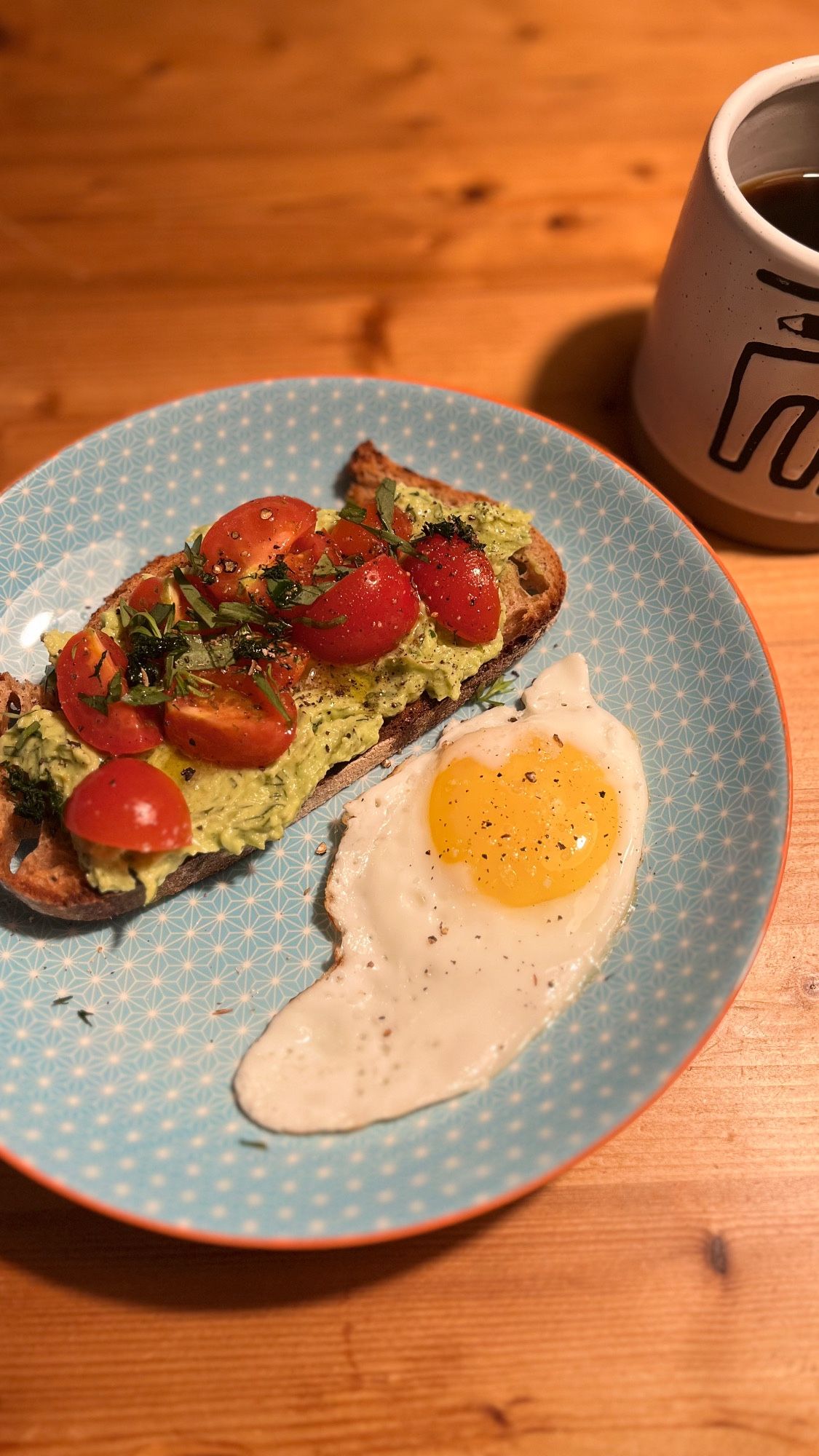 Teller mit Spiegelei und einer üppig mit Abvocadocreme und Tomatensalsa belegten Scheibe Brot.