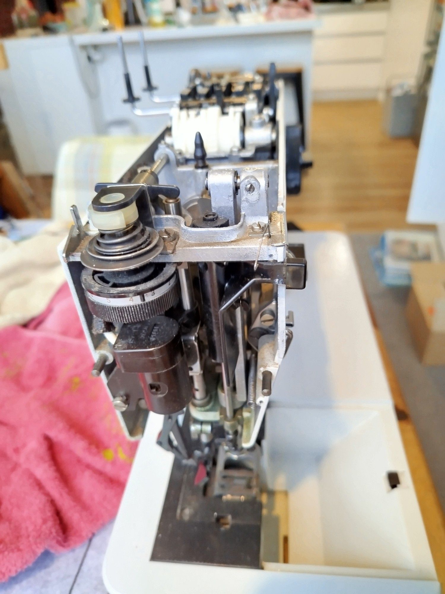 The left hand side of the sewing machine showing upper tensioner and presser foot bar