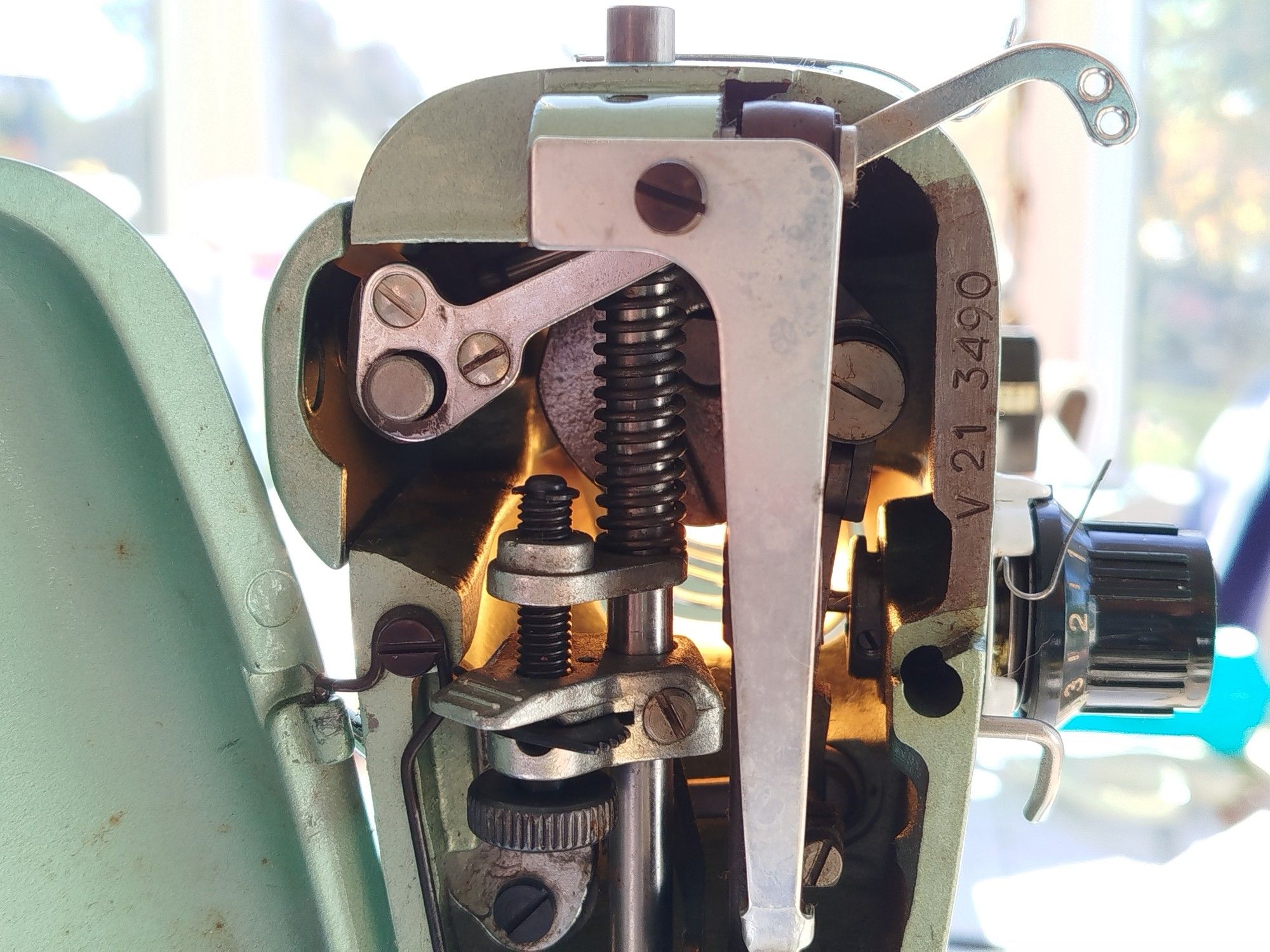 A view from the left, looking into the machine. The presser bar is visible inside, and the take up thread tensioner on the outside.