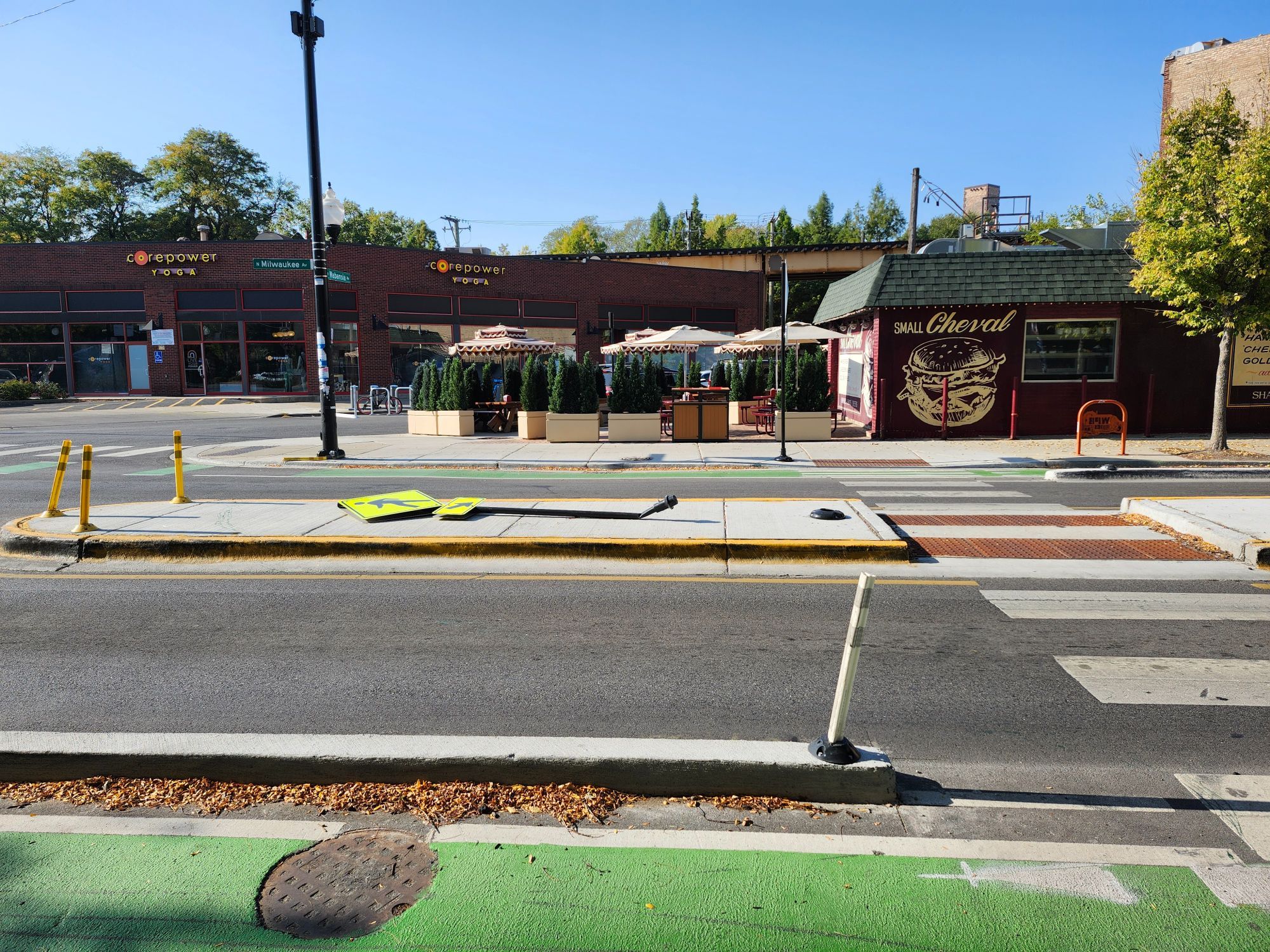 A pedestrian crossing sign in a concrete median island, pancaked flat on the ground