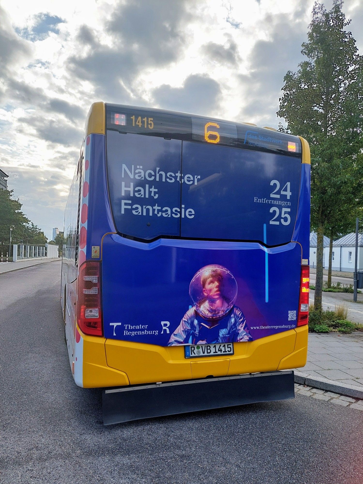 Rückseite eines Busses mit blauer Werbung für Theater Regensburg & Aufschrift "Nächster Halt Fantasie".