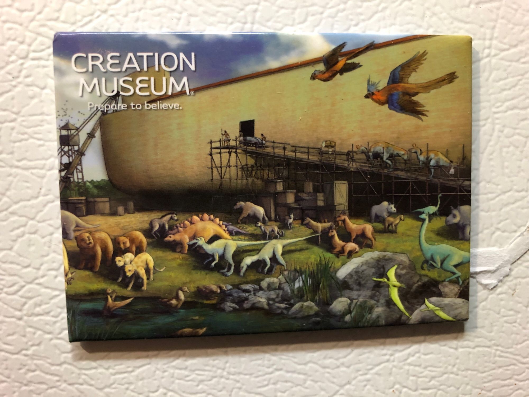 A refrigerator magnet with a picture of Noah’s Ark in the background, being loaded with various prehistoric animals, while dinosaurs roam about, either waiting their turn or preferring to drown. 
Text reads: 
CREATION MUSEUM 
Prepare to believe.