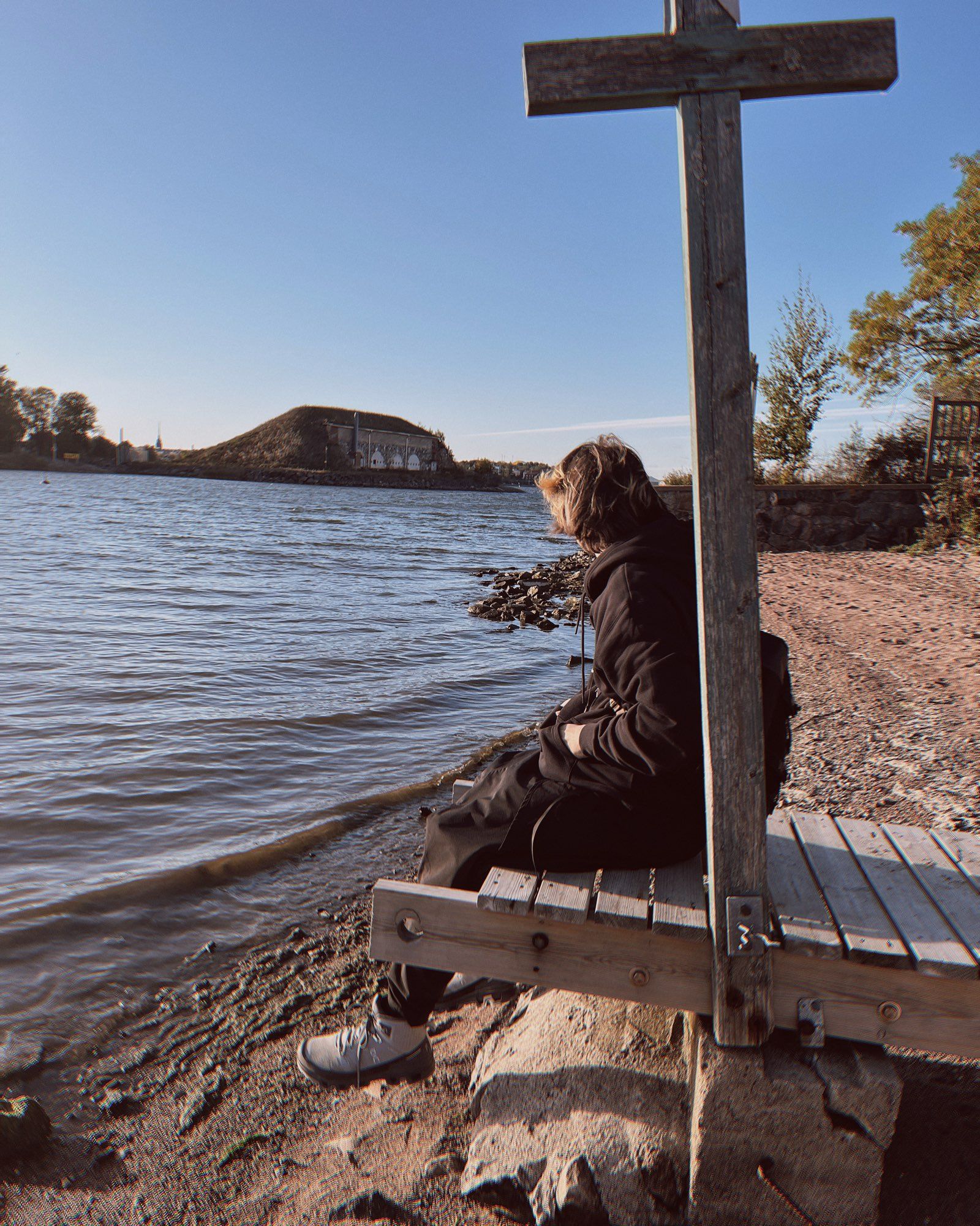 a guy in black sitting by the sea