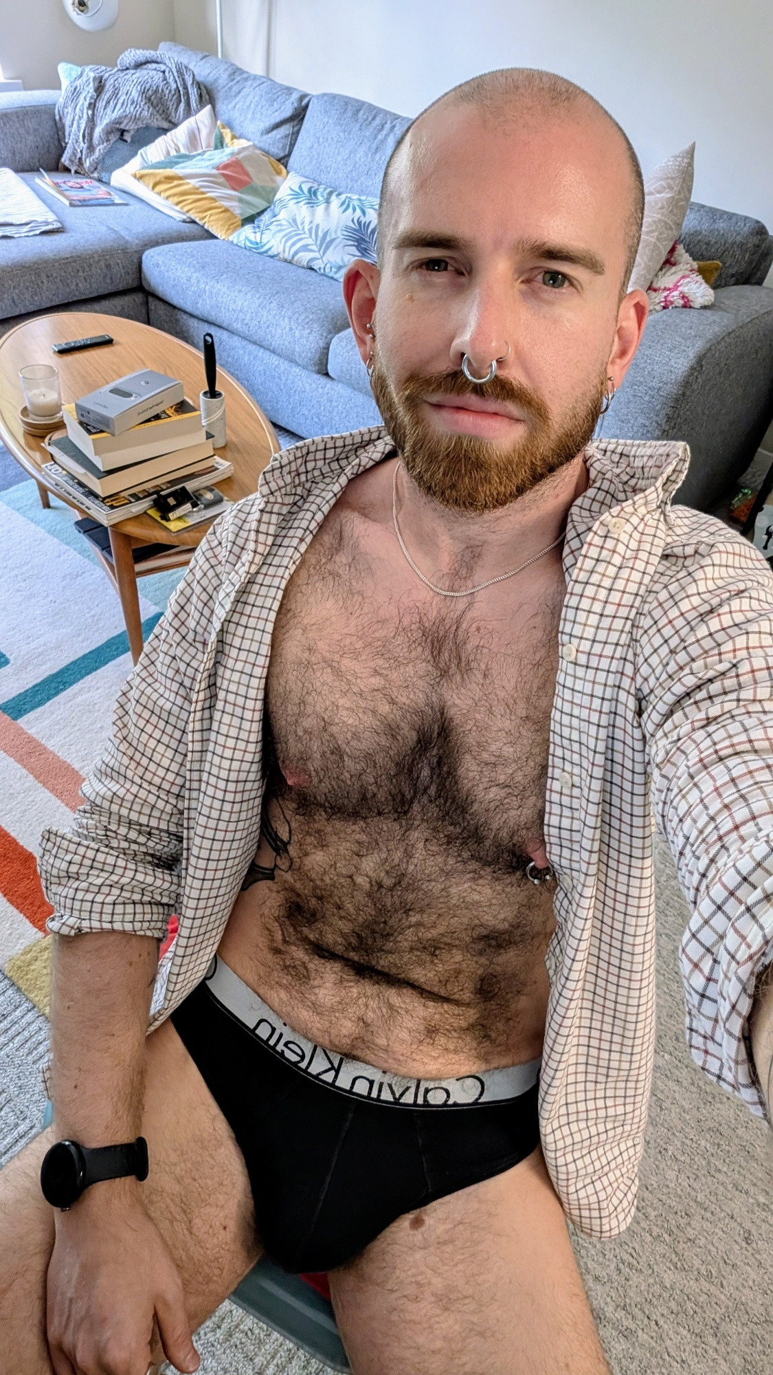 Man sat on chair in briefs and open shirt. 