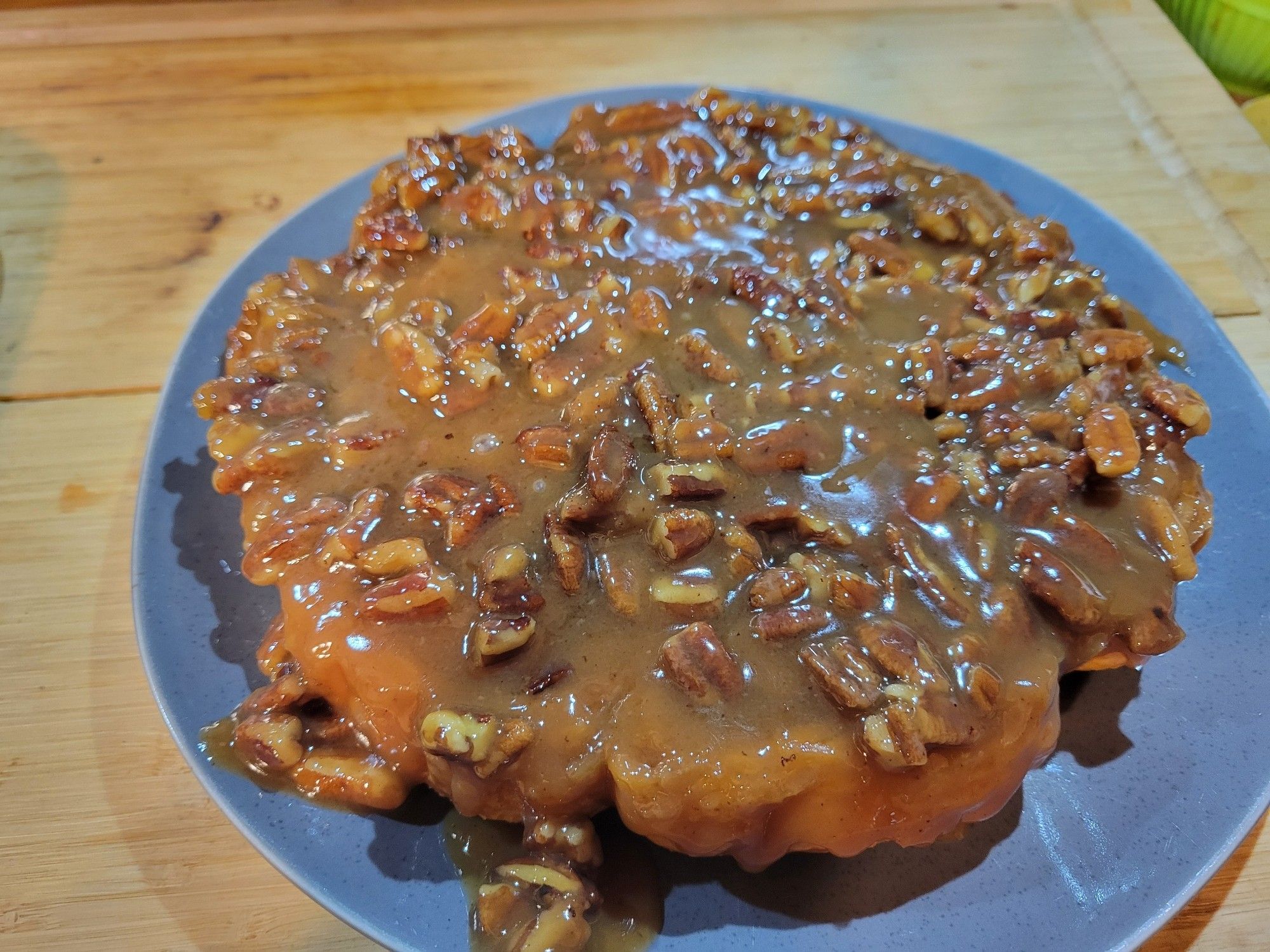 A grey plate of sticky buns (cinnamon rolls covered in pecan pieces and caramel sauce.