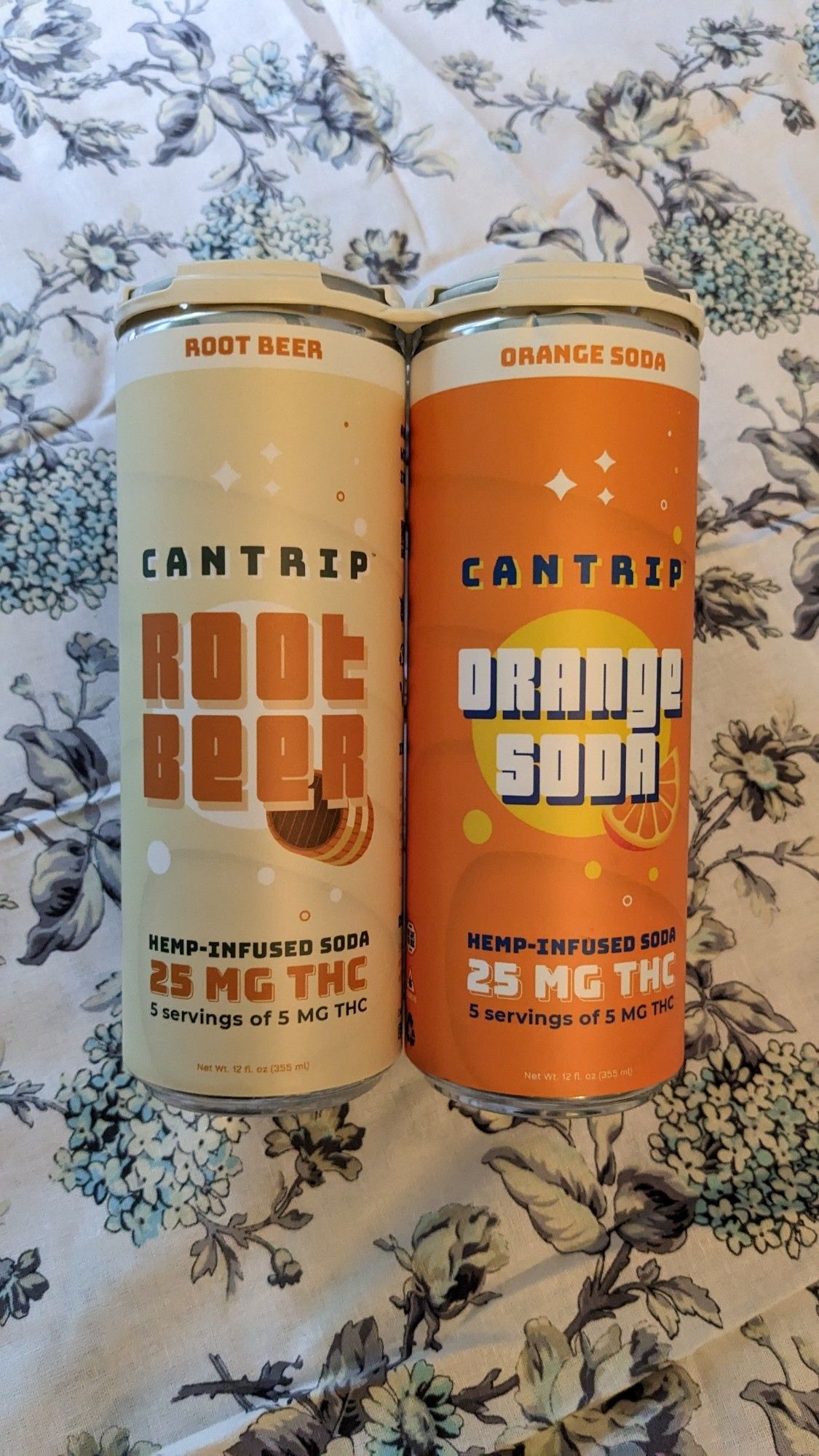 THC root beer and orange soda, 25mg cans, on a floral print background