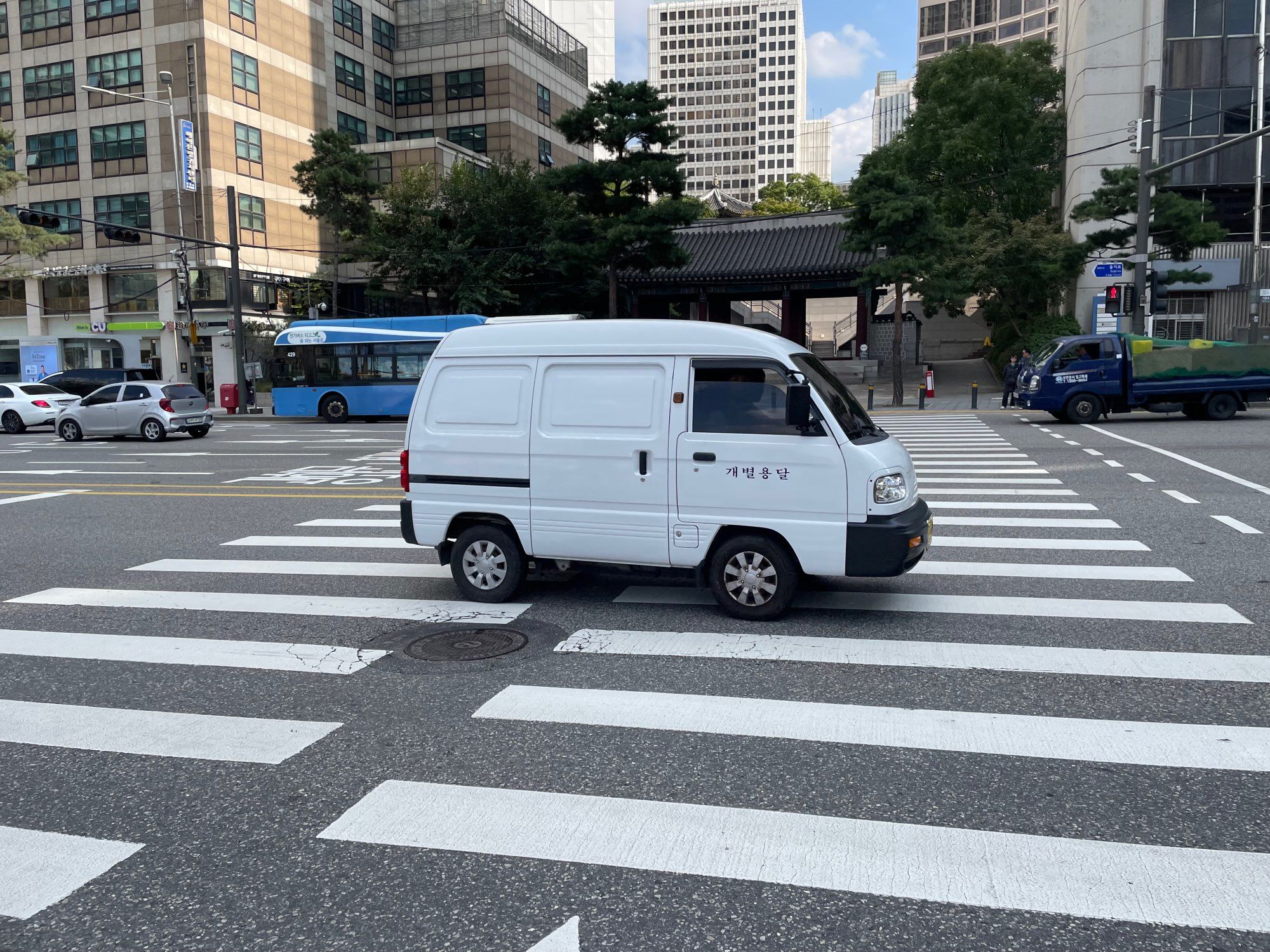 A very small white van on a street in Seoul.