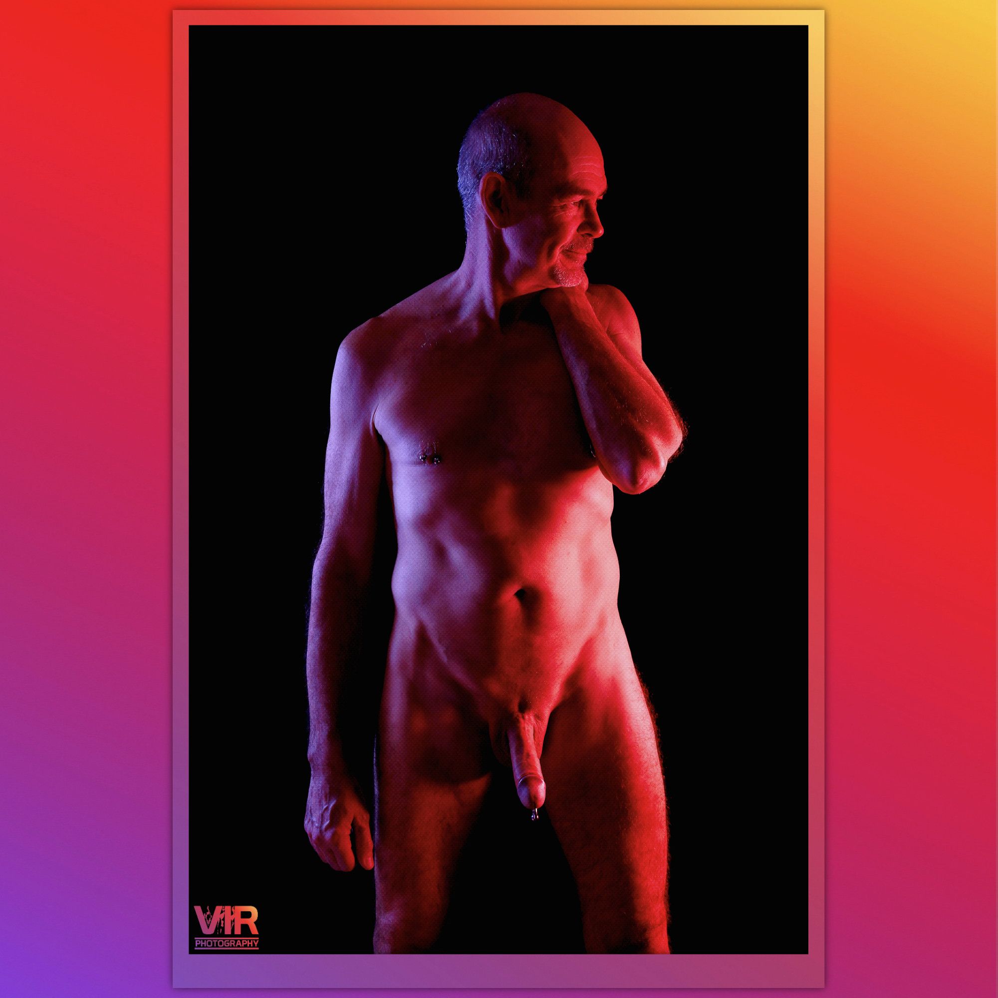 Image of a nude male model taken under colour gel lights. The model has a prince albert style piercing.