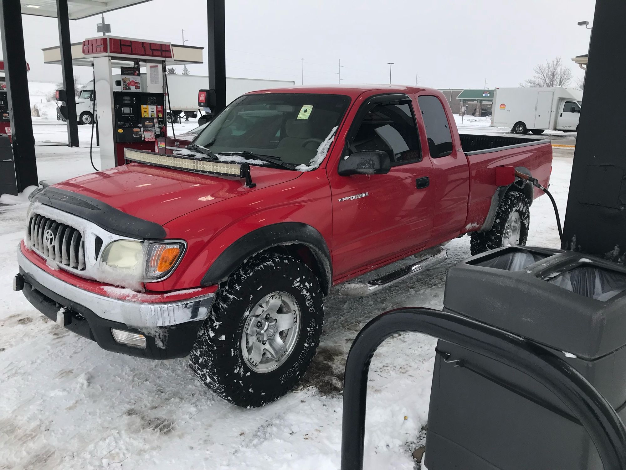 A red Toyota Tacoma truck in the snow