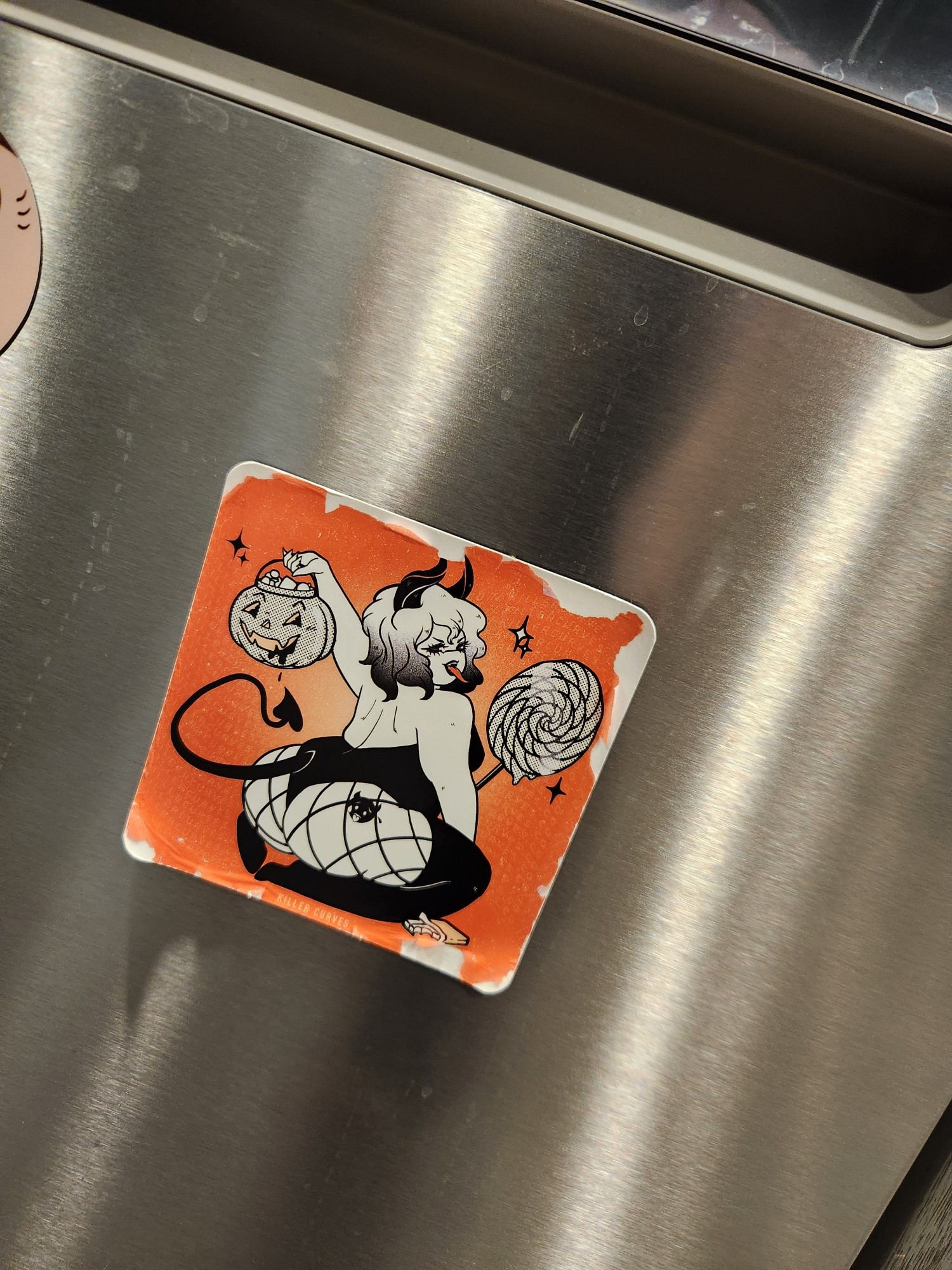 A thicc as hell demon girl Halloween magnet on a dishwasher