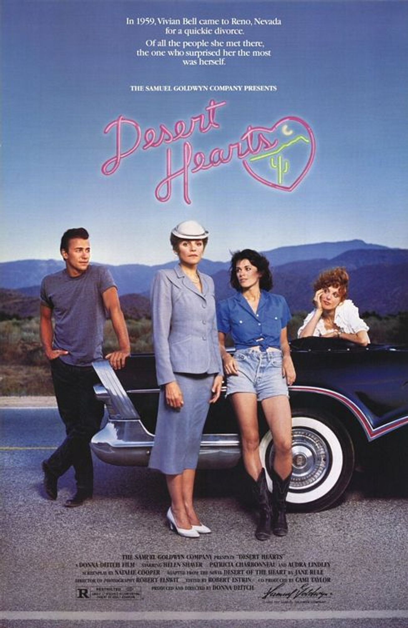 A poster for the film Desert Hearts. A stiff, well-dressed woman stands on the road, while a sexy younger woman leans against a classic black convertible and stares at her. The two are watched by a man in a t-shirt and a red-haired woman in the back seat of the car.